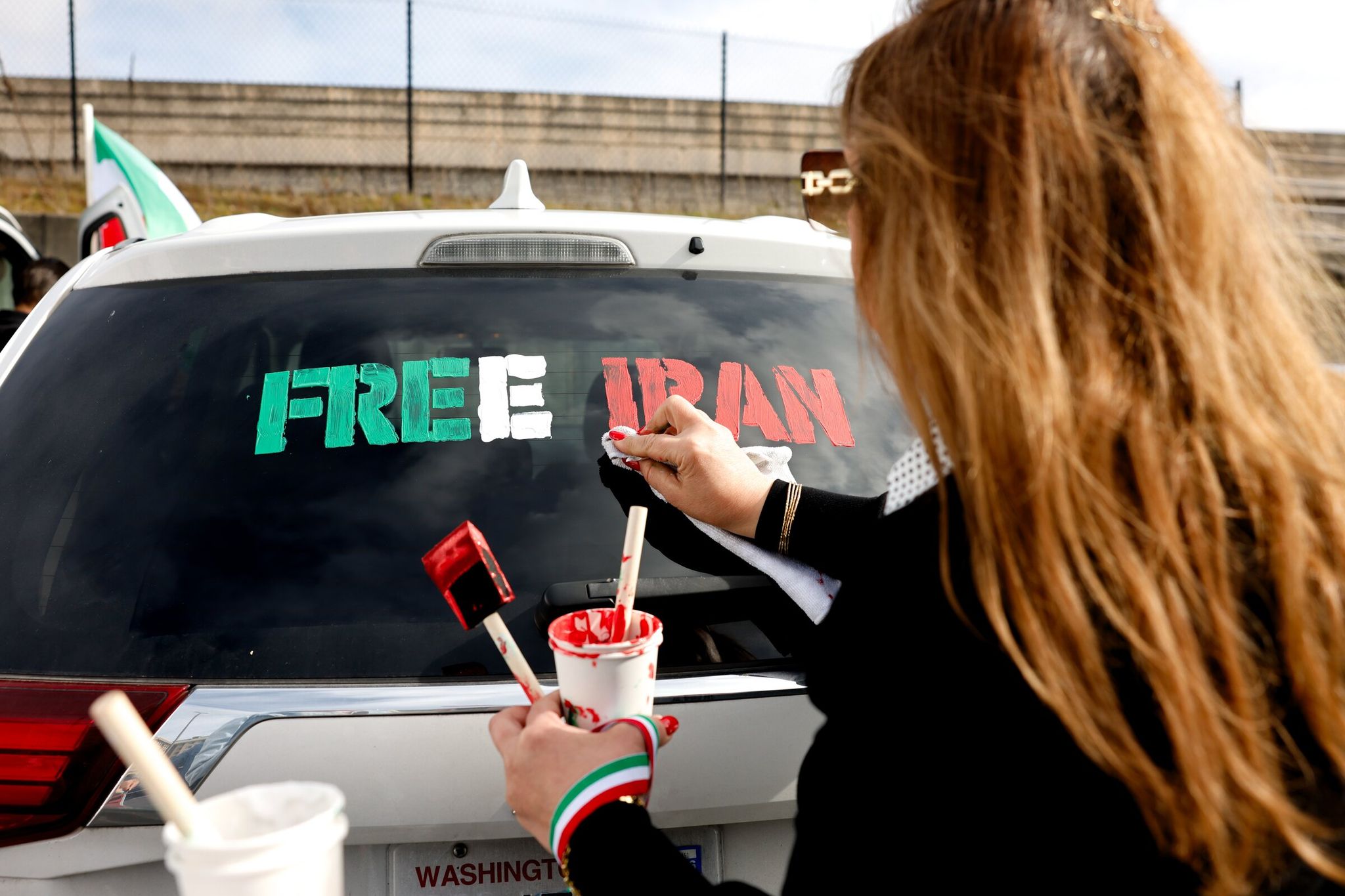 Сепиде Дараб рисует «Свободный Иран» смываемой краской на задней части автомобиля на автомобильном митинге в Белвью 28 февраля в ответ на бомбардировке Ирана. (Карен Дюси / The Seattle Times)