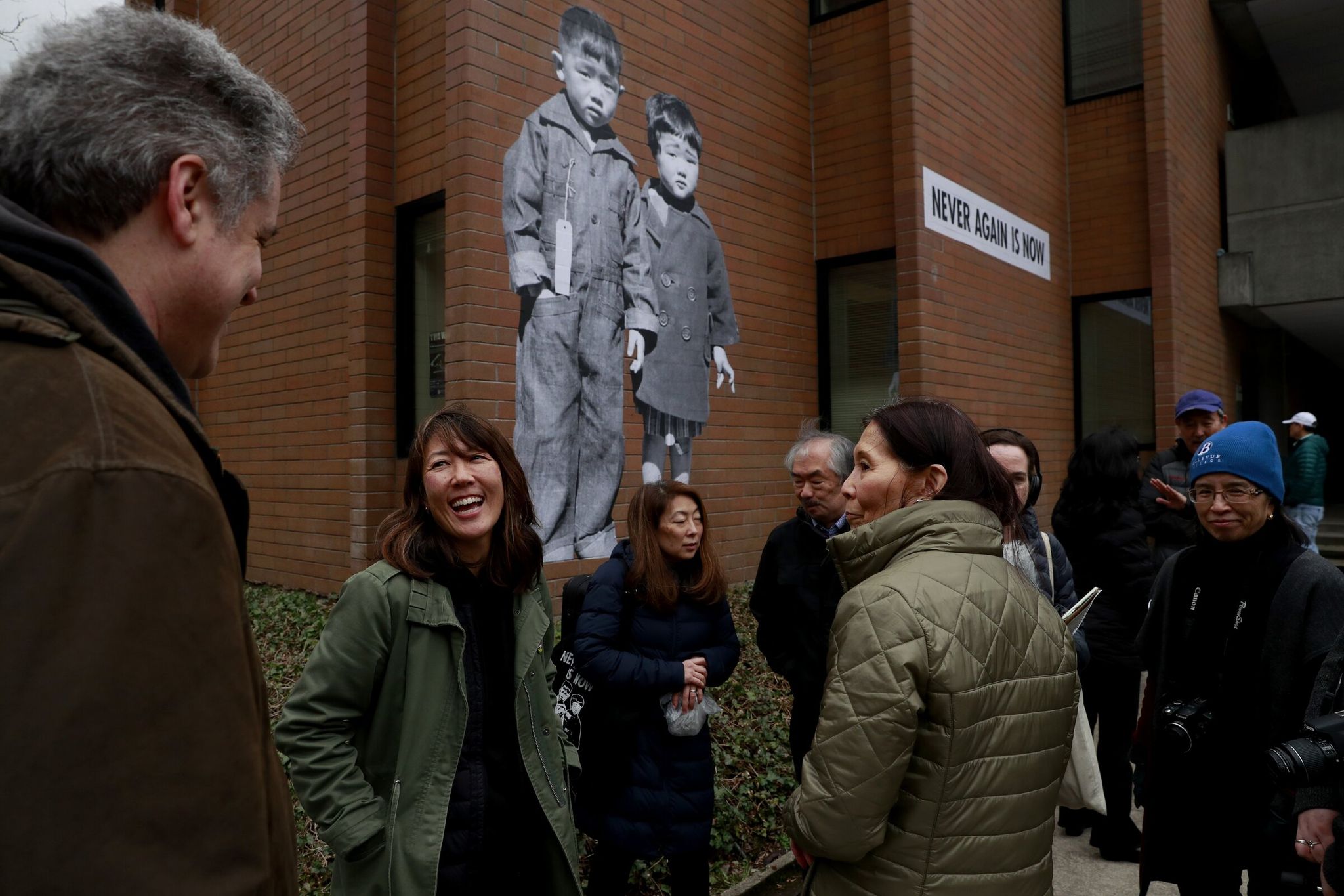 Сиэтлская художница Эрин Сигаки (второй слева) беседует с людьми в колледже Бельвью, где была установлена её фреска «Никогда снова — это сейчас», изображающая двух японо-американских детей в лагере интернирования. (Erika Schultz / The Seattle Times, 2020)