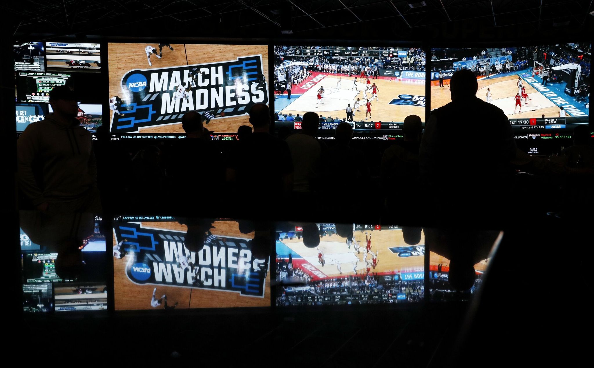 People watch coverage of the first round of the 2018 NCAA college basketball tournament at the Westgate Superbook sports book in Las Vegas. The governing body for college sports announced in 2018 a “temporary” lifting of a ban that prevented events like college basketball’s NCAA Tournament from being hosted in states that accept wagers on single games. (John Locher / AP)