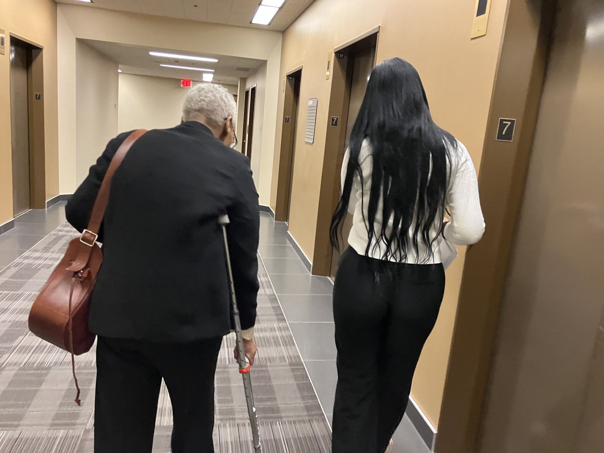 A Venezuelan woman, right, walks down a hallway outside Seattle’s immigration court to file a response to a government motion to deport her to Ecuador. (Nina Shapiro / The Seattle Times)