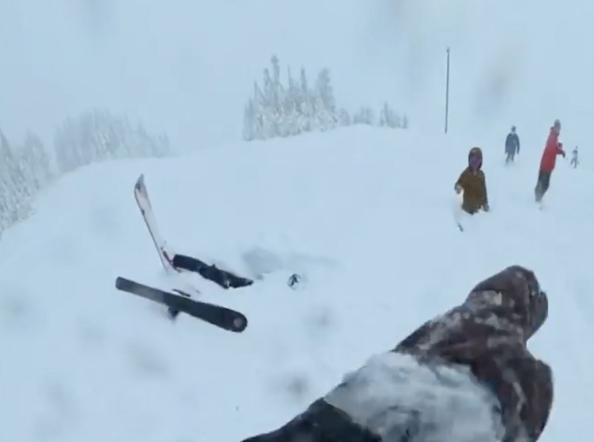 In this screen grab from Ian Deans’ video, a skier is seen stuck under deep snow after falling at the Summit at Snoqualmie ski resort Friday. (Courtesy of Ian Deans)
