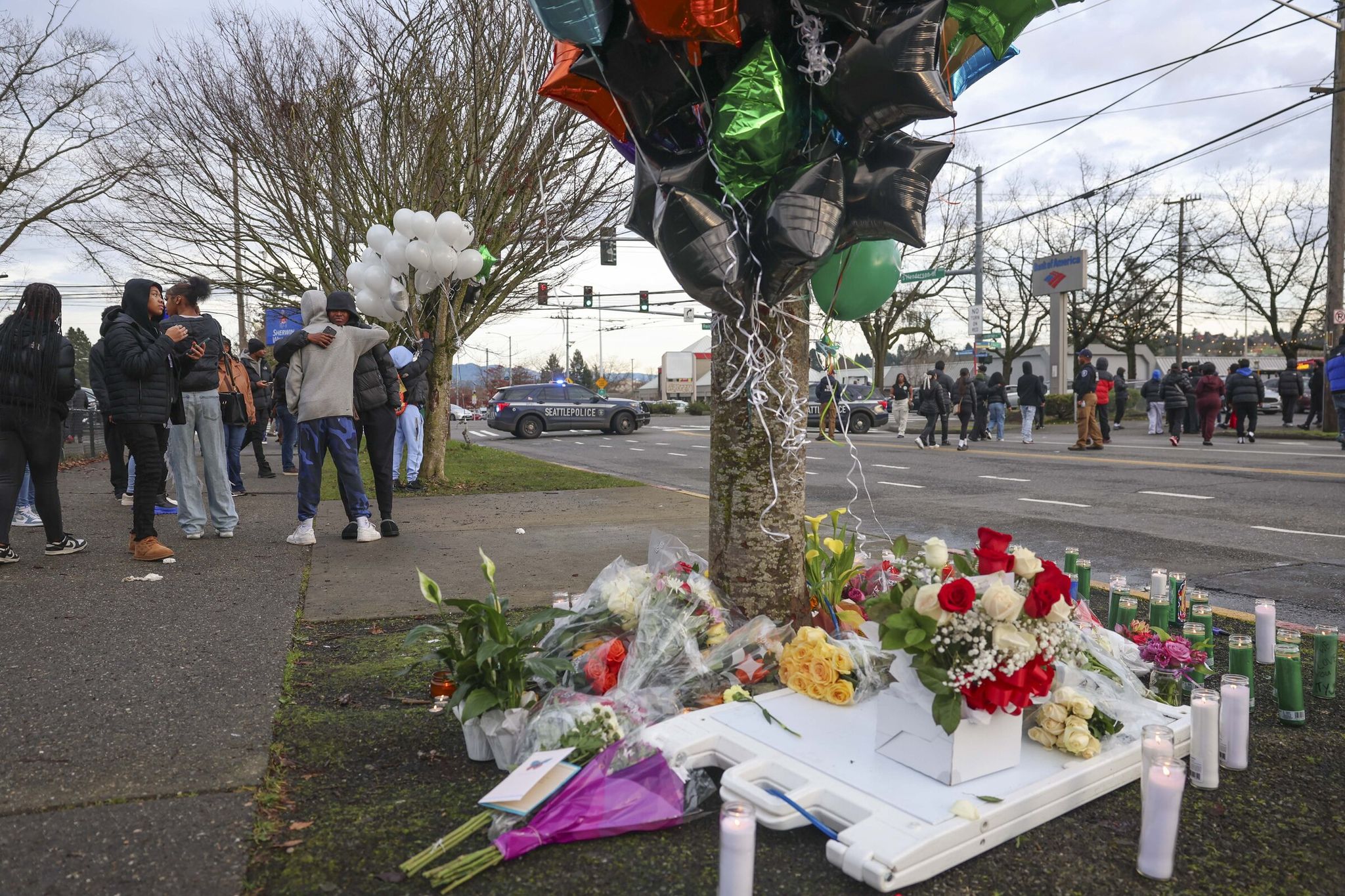 People visit a memorial near the spot where two teenagers were shot and killed at a bus stop on Jan. 30 in Rainier Valley, Seattle. (Ivy Seballo / The Seattle Times)