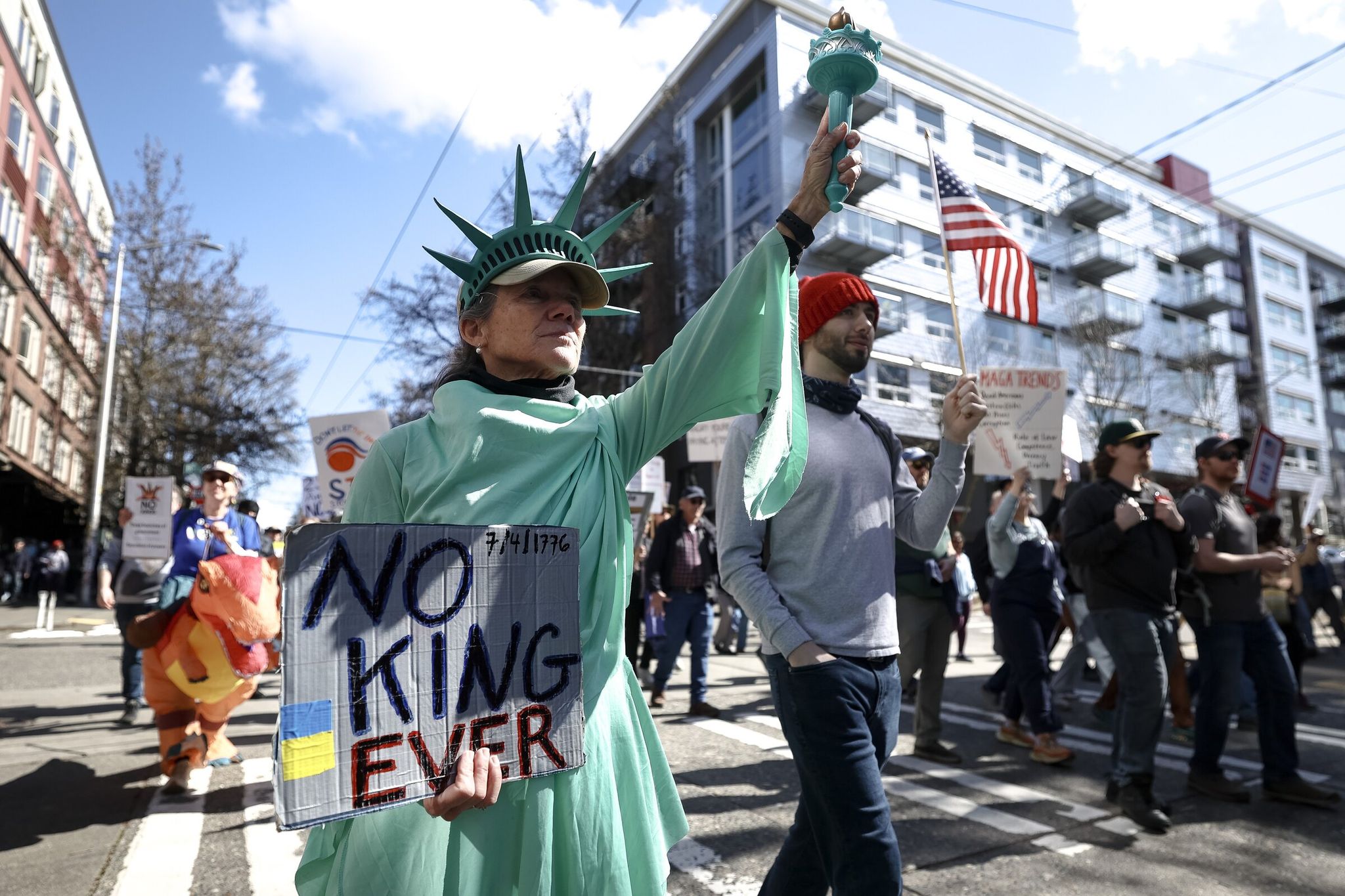 Sue Nevler, dressed as the Statue of Liberty, and her son Miles march at the 'No Kings' protest in Seattle on Saturday. (Nick Wagner / The Seattle Times)