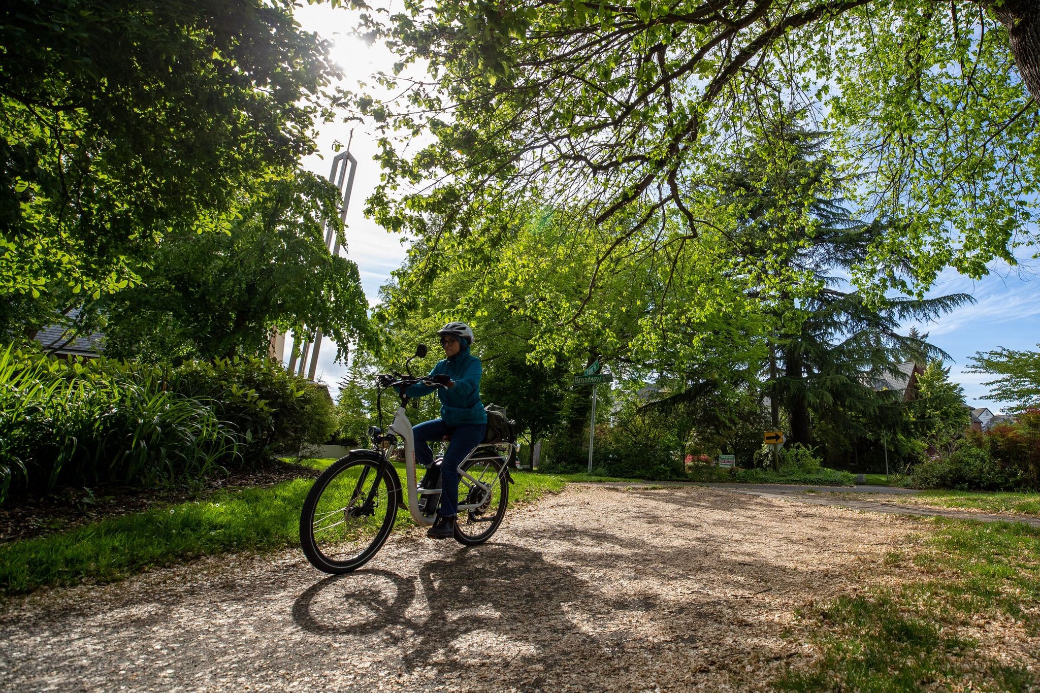 A rider on an electric bicycle rides through a sunlit patch, passing through Roanoke Park on Friday, May 27, 2022, in Seattle, Washington. (Jennifer Buchanan / The Seattle Times)