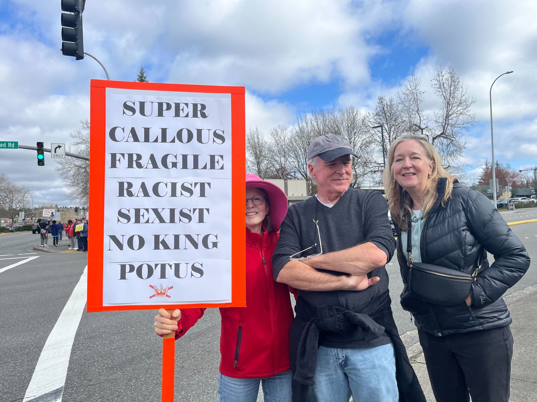 Kristen Newell (left) holds a sign she made Saturday morning for the No Kings protest in Bellevue. (Stephannie Stokes / The Seattle Times)