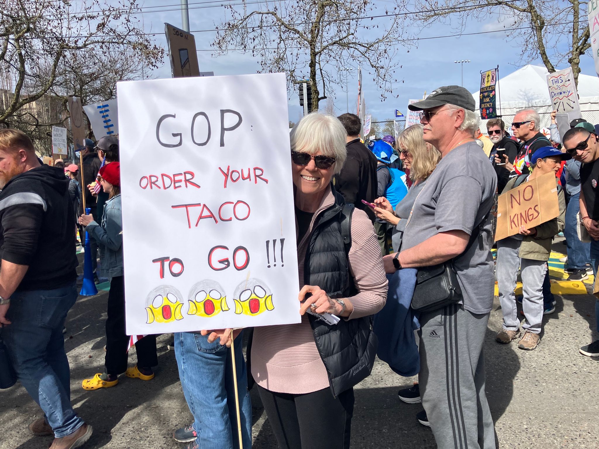 Protester Kate Aigou's sign hints at the acronym 'TACO': Trump Always Cowers Out. (Nina Shapiro / The Seattle Times)