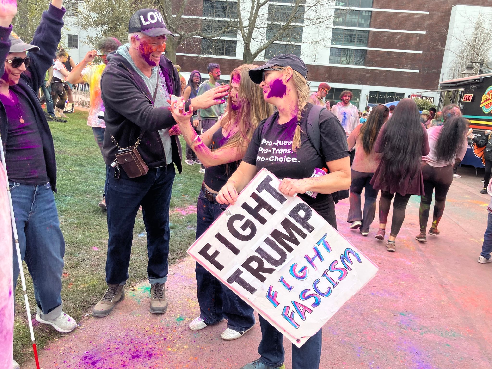 A 'No Kings' protester joins Seattle's Holi Festival at Seattle Center. (Nina Shapiro / The Seattle Times)