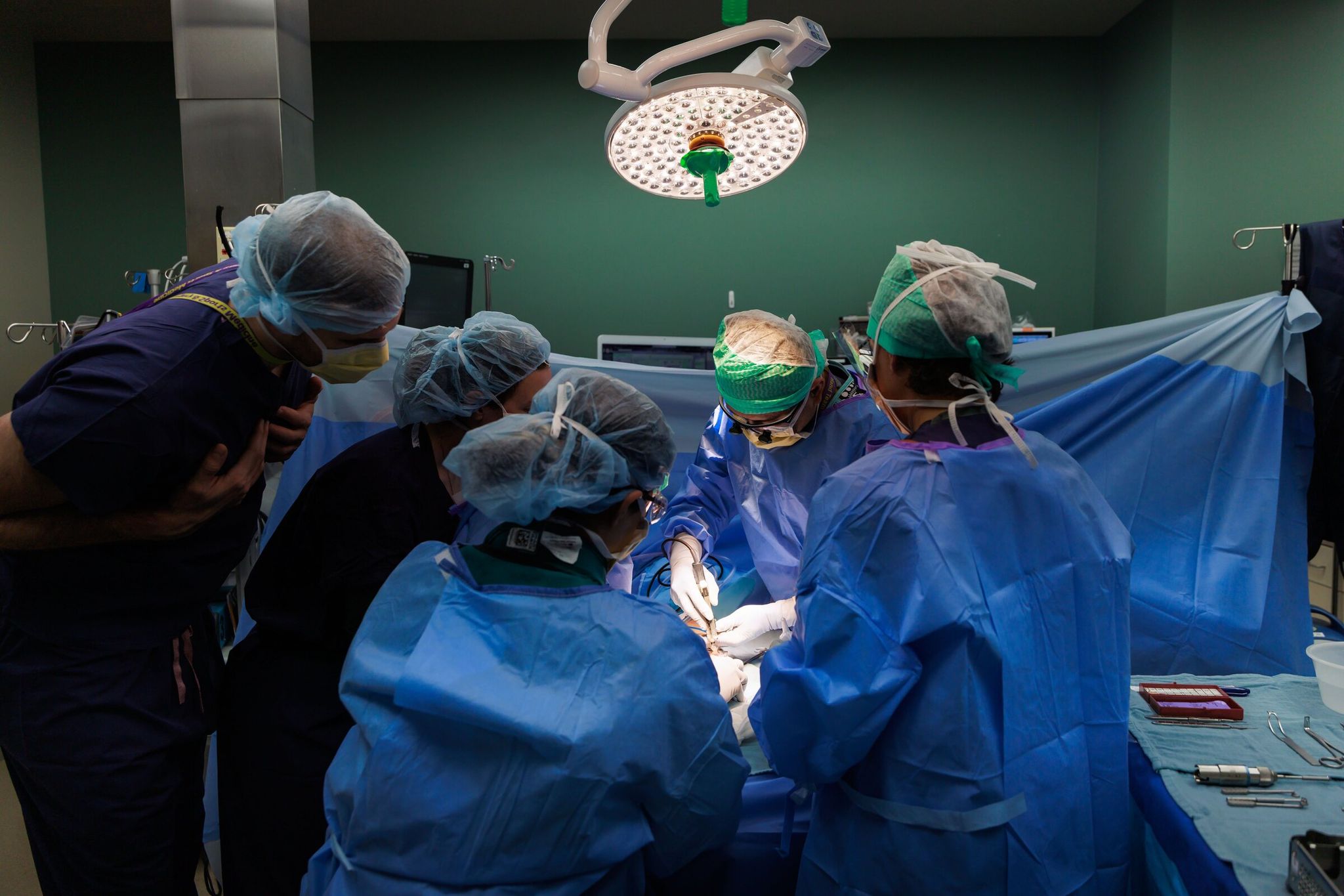 Dr. Jerry Huang, center, performs a thumb joint replacement using a prosthesis, a relatively new procedure in the United States, at UW Medical Center — Roosevelt last week. (Erika Schultz / The Seattle Times)