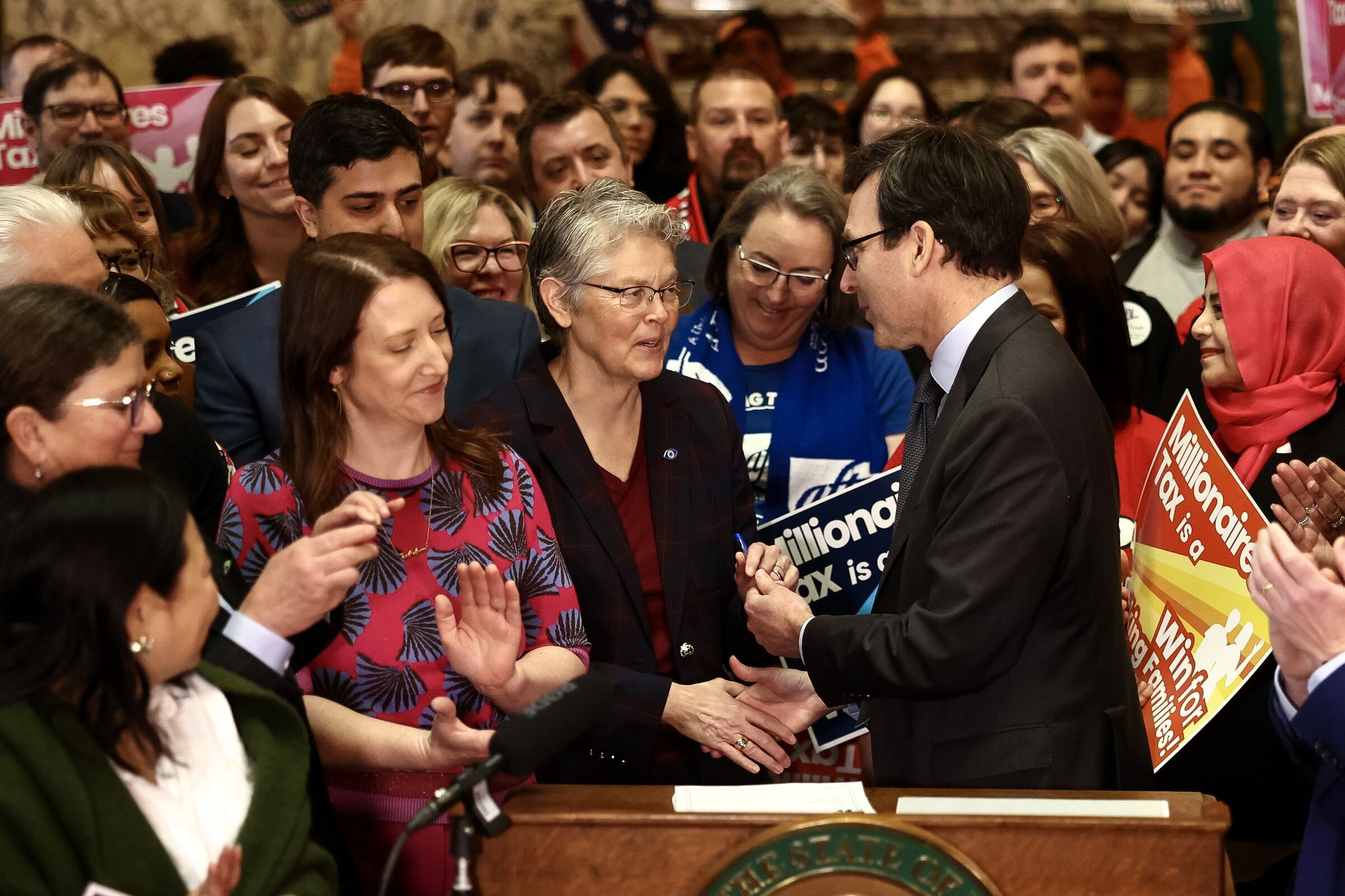 Governor Bob Ferguson hands the pen used to sign the high-earners tax bill to House Speaker Laurie Jinkins at the state Capitol on March 30 in Olympia. (Nick Wagner / The Seattle Times)