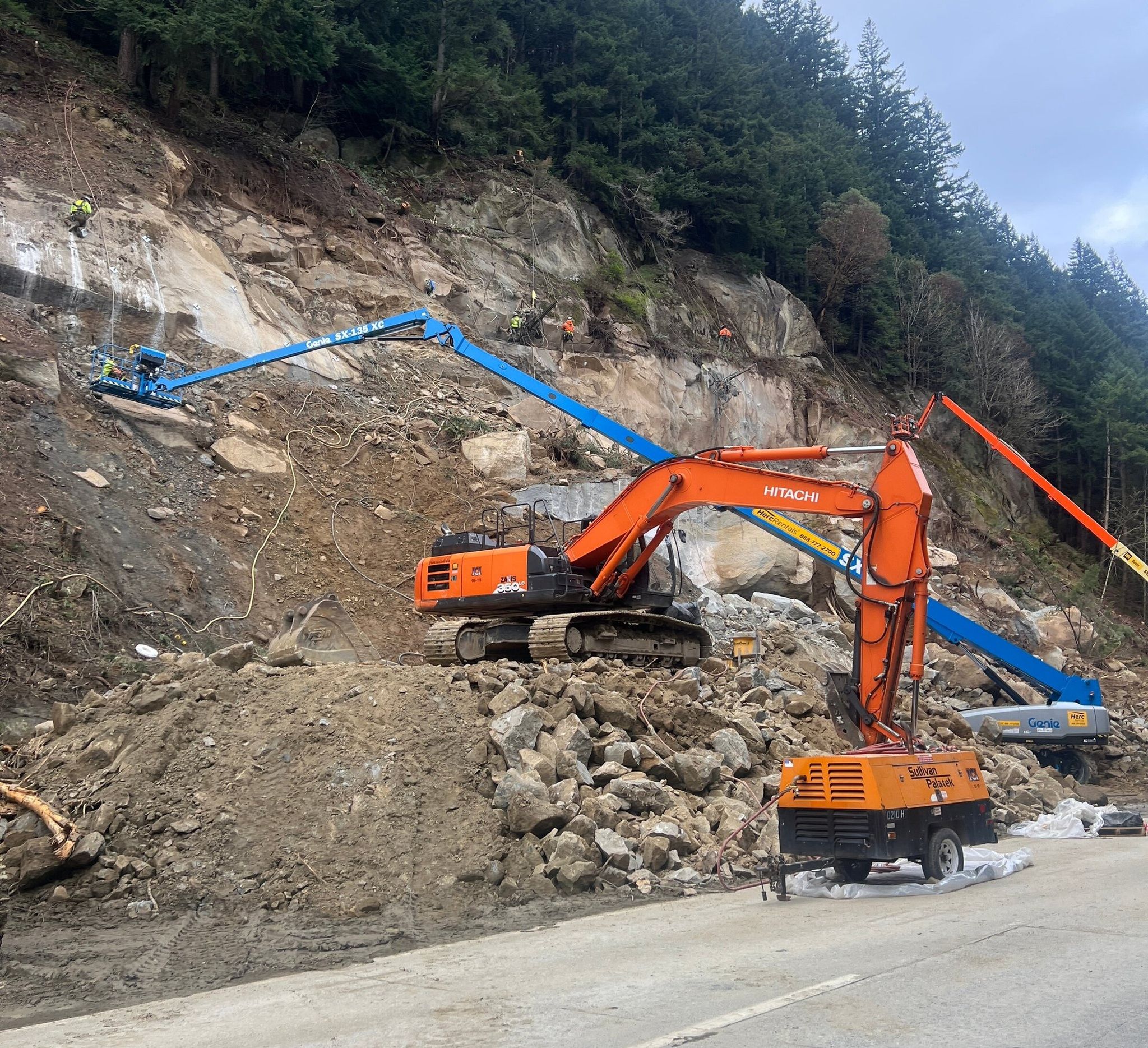 Crews drill and anchor steel rods into the rock face at the site of the March 19 landslide that closed northbound I-5 south of Bellingham. The rods will help stabilize the slope. (Washington State Department of Transportation)