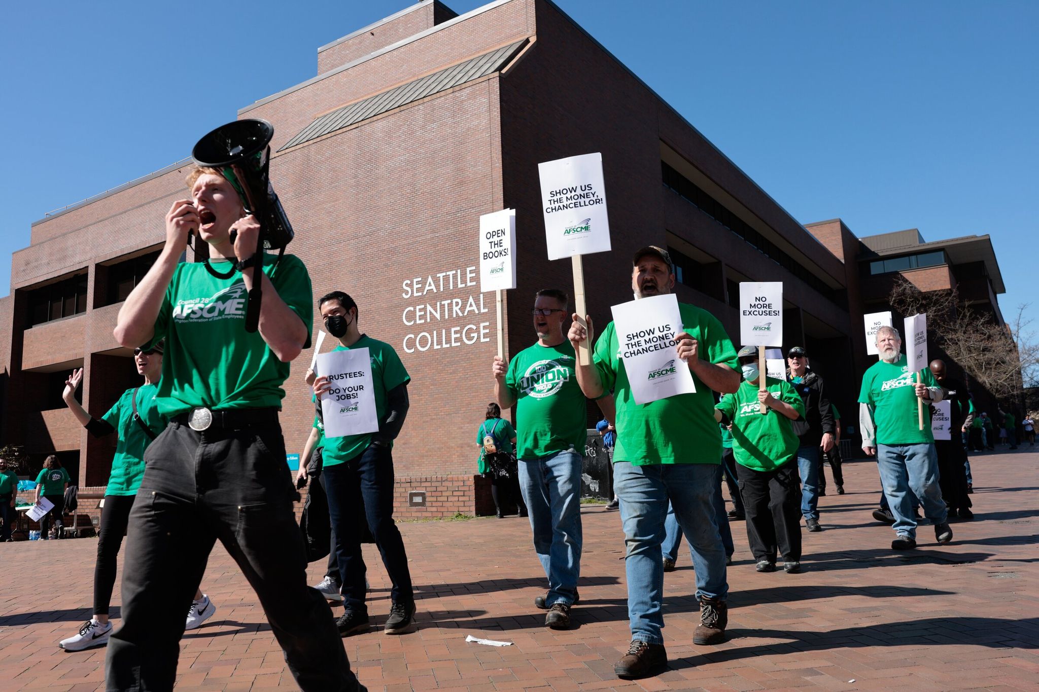 At left, Forest Williams leads chants while members of WFSE Local 304 protest before the Seattle Colleges board meeting at Seattle Central College on Thursday. Union members joined students who study at the Wood Technology Center — a Seattle Central program whose building could be sold to cover a budget shortfall — in contesting a possible sale. (Karen Ducey / The Seattle Times)
