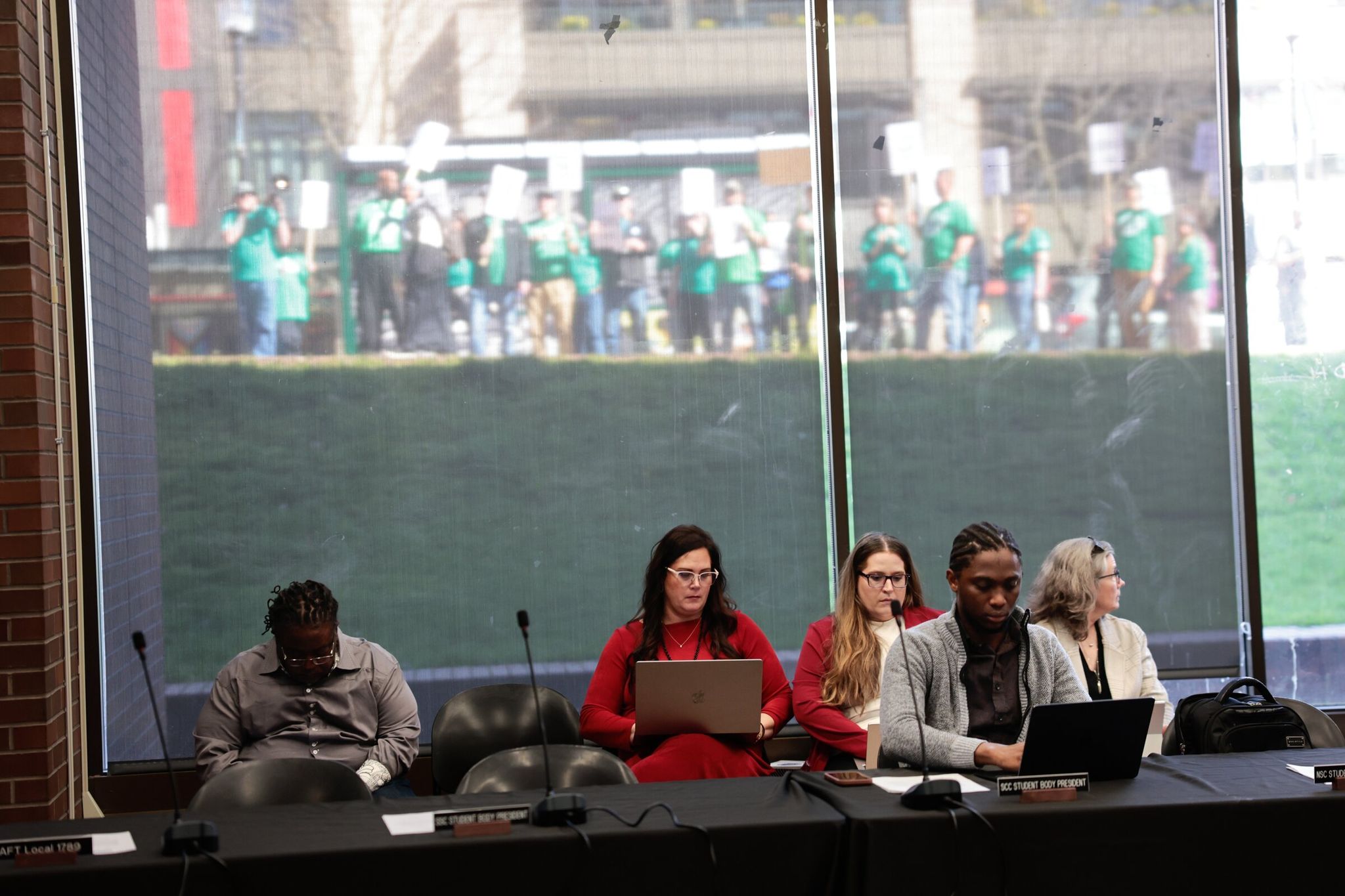Members of WFSE Local 304 protesting outside were heard inside the Seattle Colleges board meeting on Thursday. Barb Childs, Seattle Colleges’ spokesperson, sits center. (Karen Ducey / The Seattle Times)