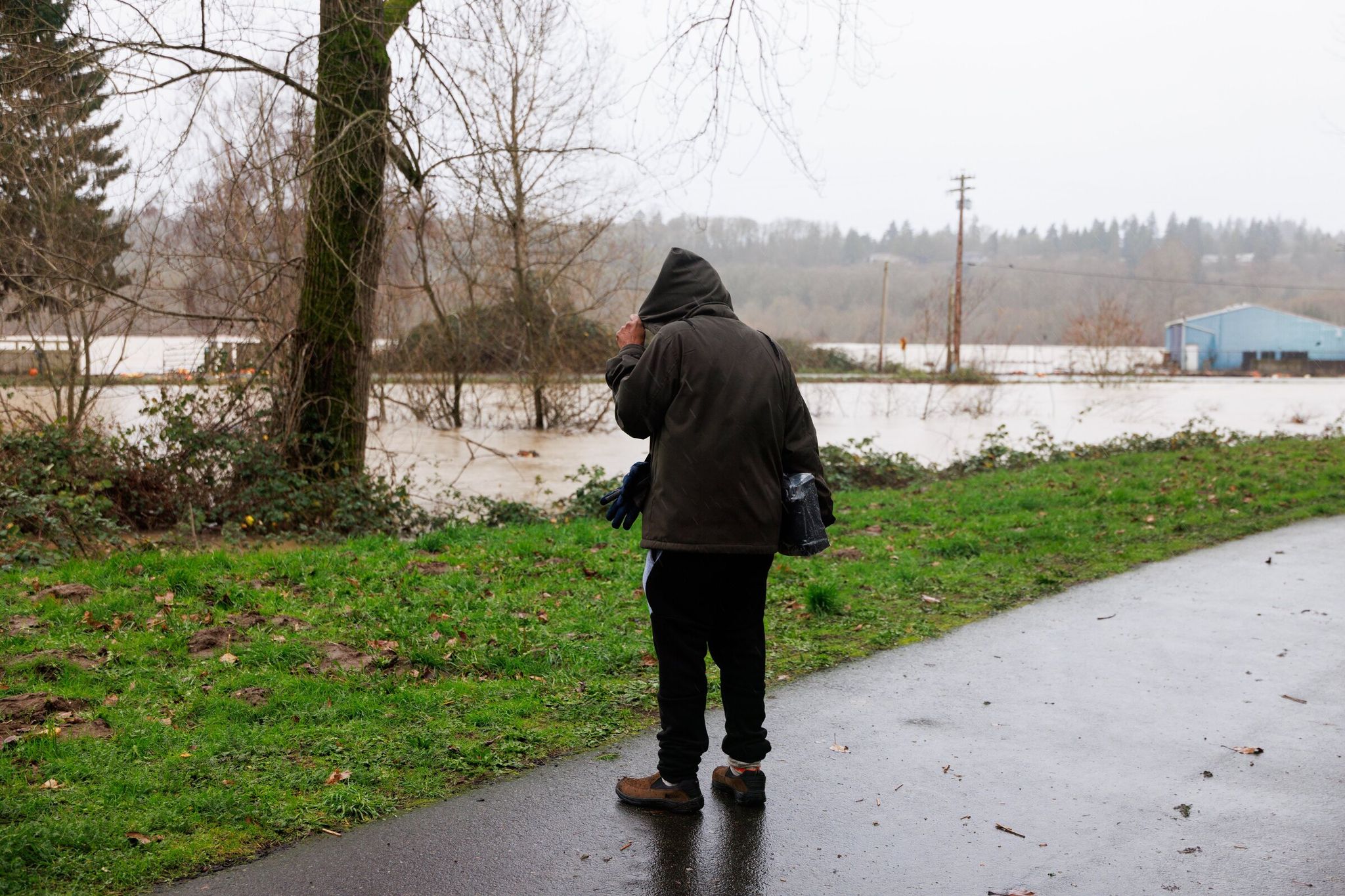 A person walks beside the Signature Pointe Apartment Homes and the flooded Green River in Kent on Dec. 16, 2025. (Erika Schultz / The Seattle Times)