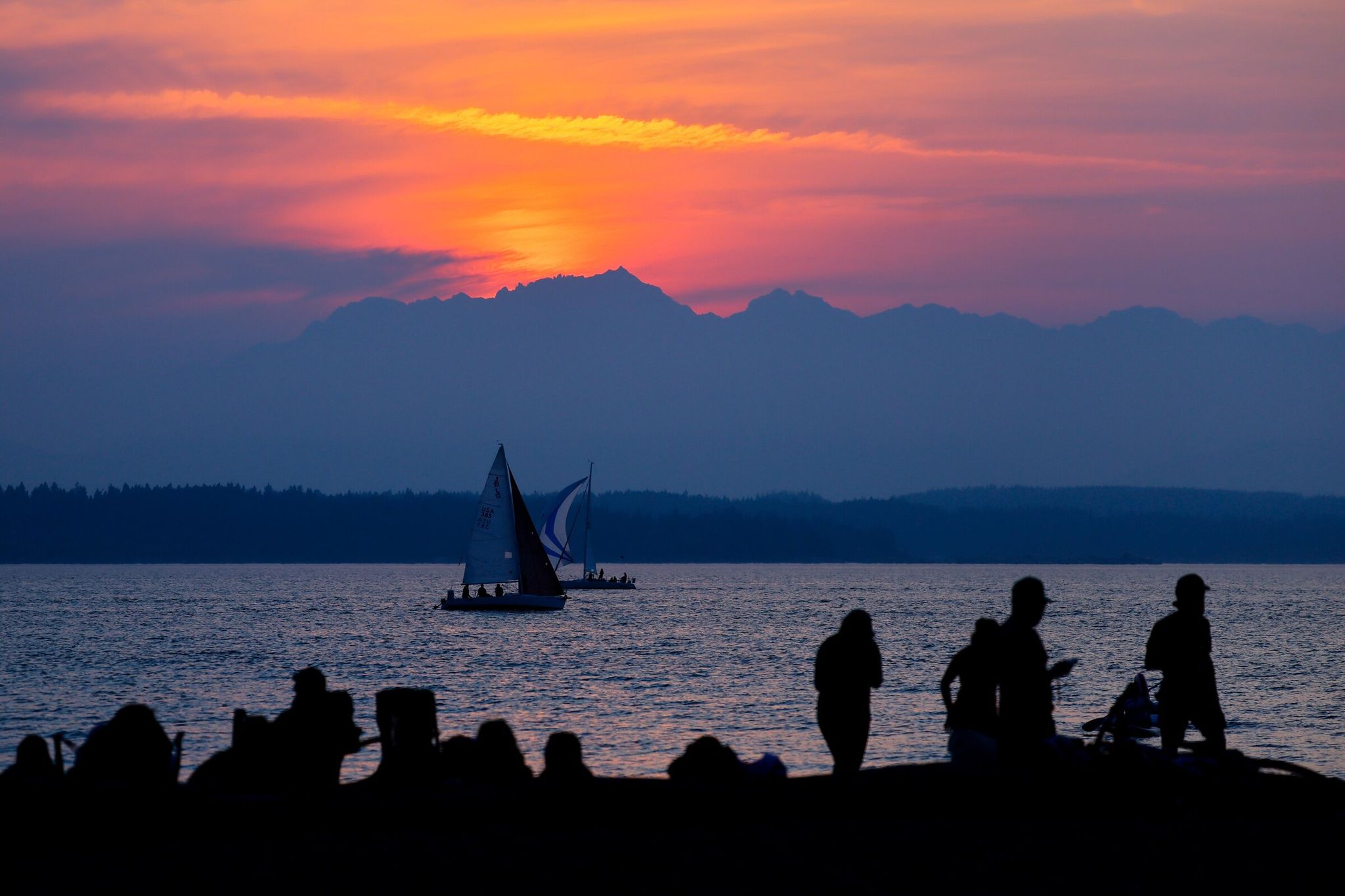 Boats drift lazily off the Golden Gardens shoreline as the sun sets behind the Olympic Mountains. (Jennifer Buchanan / The Seattle Times, 2025)
