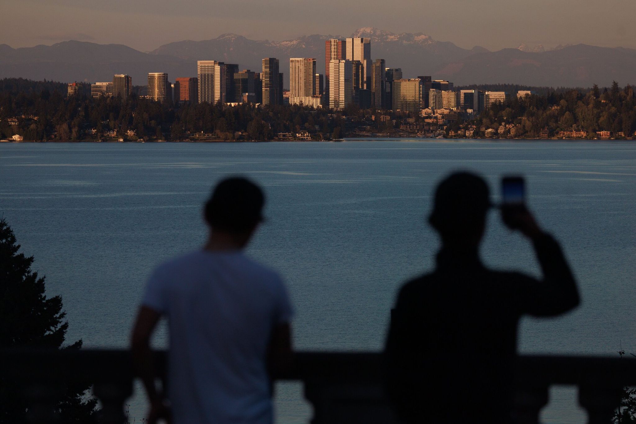 Pedestrians watch the sun set over the Cascade Mountains and Bellevue in this Seattle photo from April 7. (Erica Schultz / The Seattle Times)