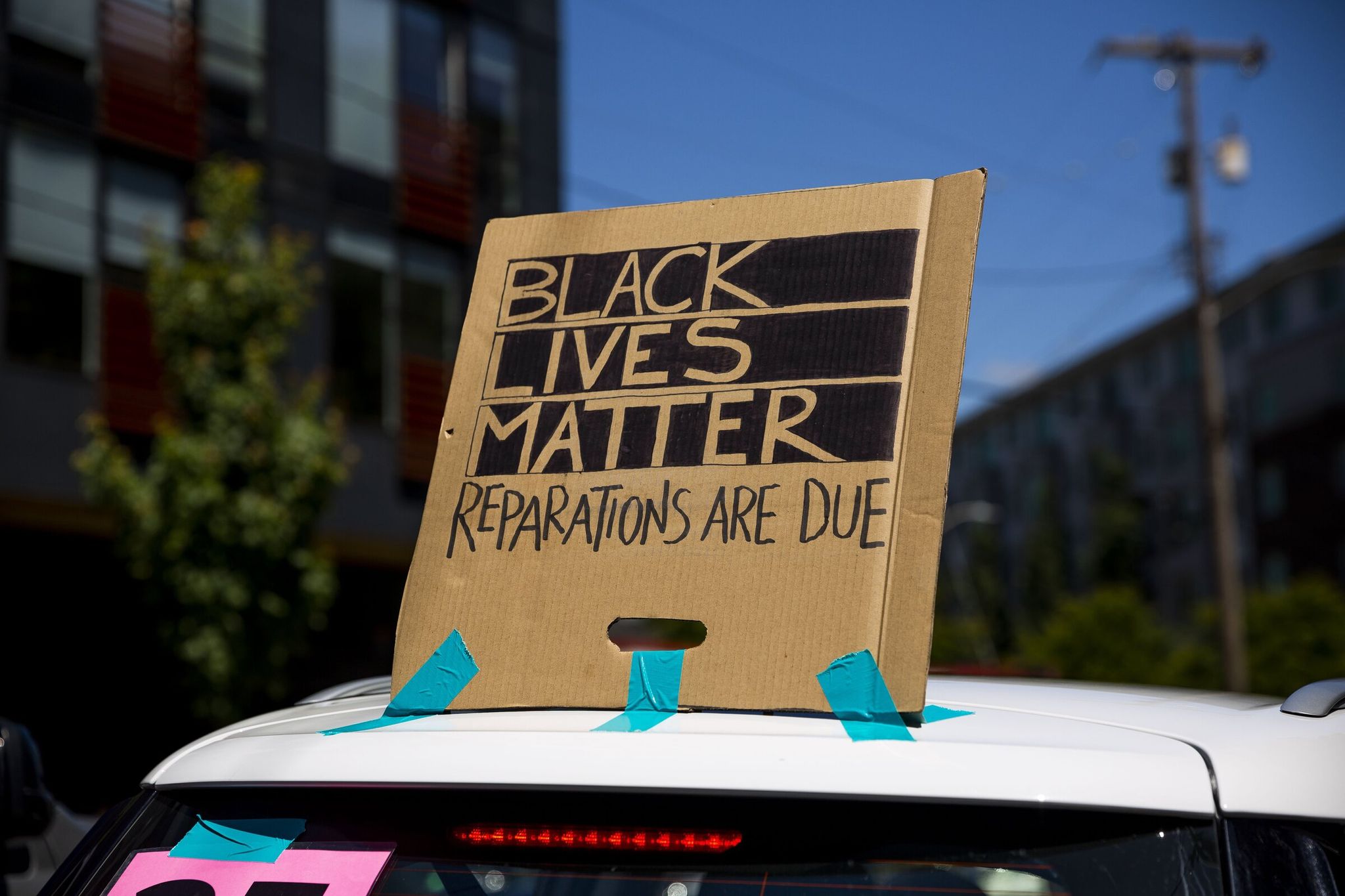 A homemade sign calls for reparations at a Juneteenth march and celebration in Seattle in 2021. (Sylvia Jarrus / The Seattle Times)