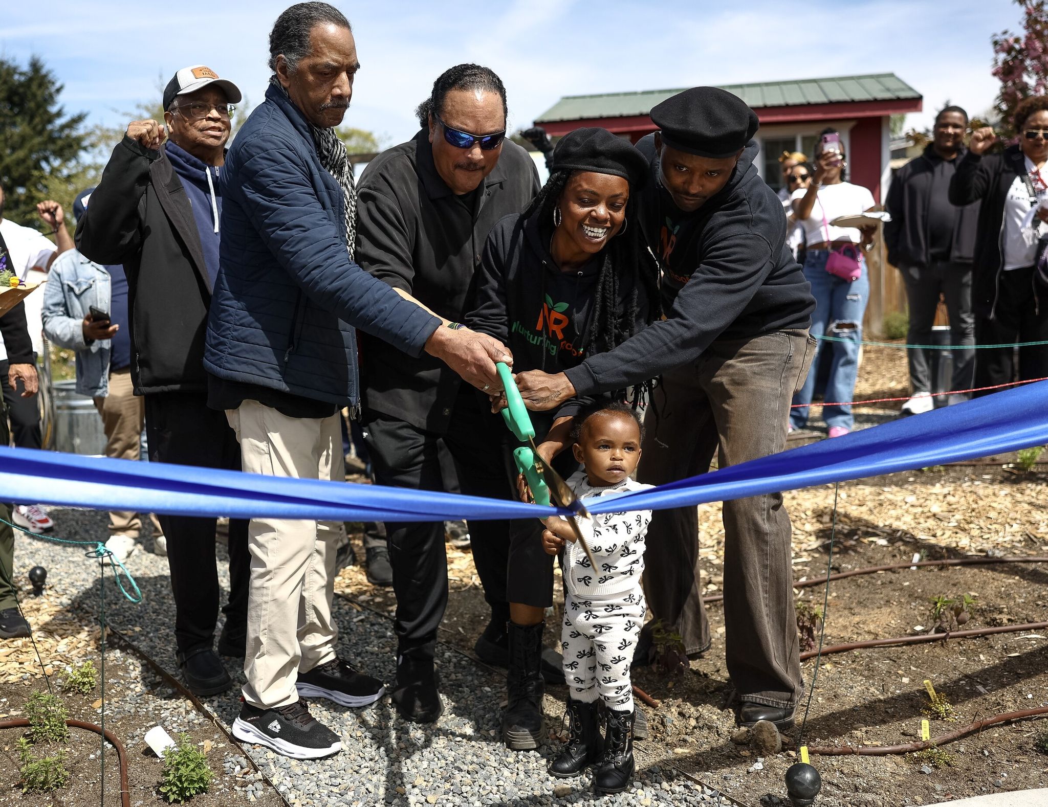 Brothers Aaron and Elmer Dixon, founders of the Seattle chapter of the Black Panther Party, help Nyema Clark, founder and executive director of Nurturing Roots, her partner Nadji Ladd-Ali and their 2-year-old daughter Nubia cut the ribbon to officially open Black Panther Park on Sunday in Skyway. (Nick Wagner / The Seattle Times)