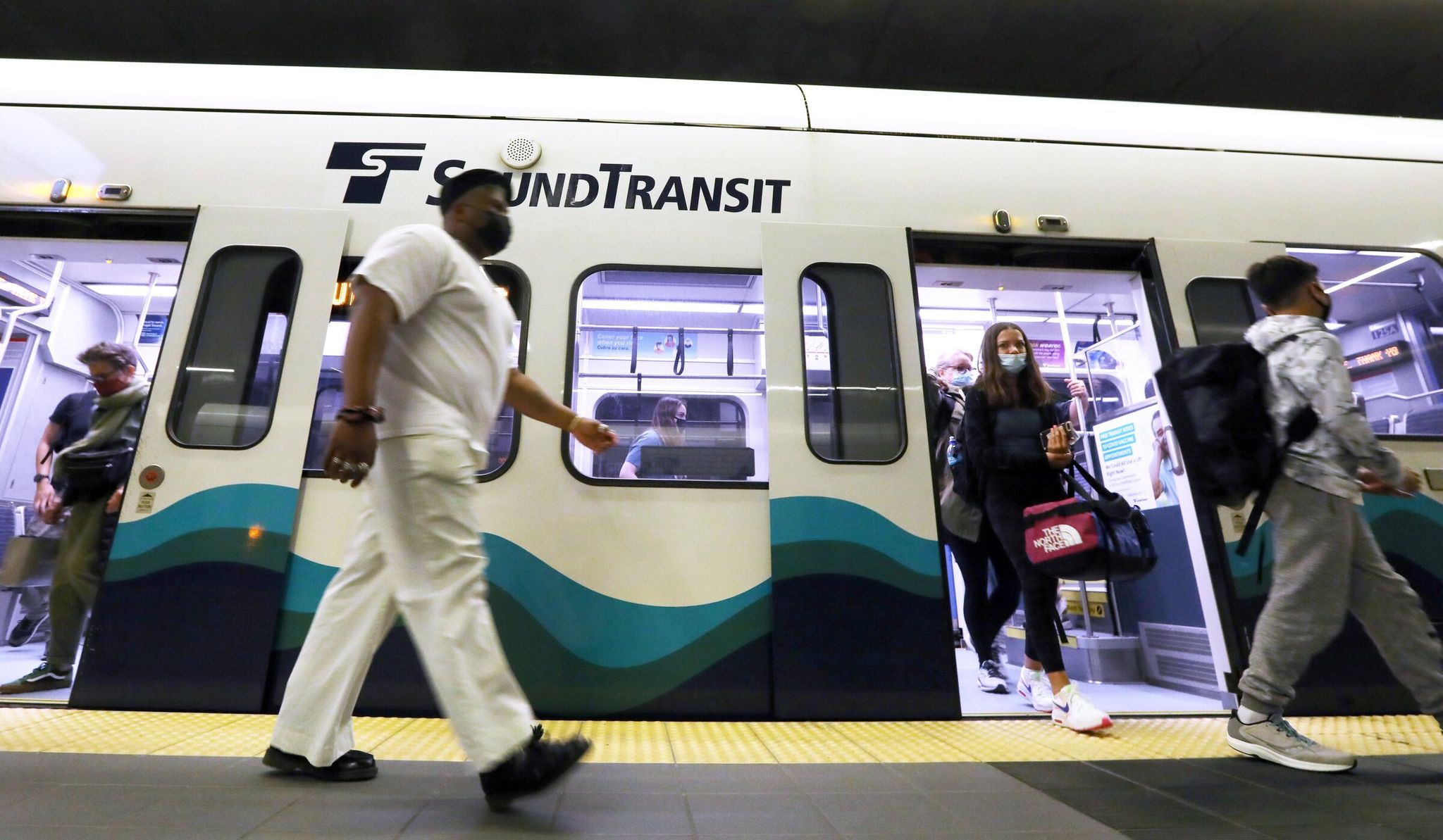 Light rail passengers are seen arriving at the University of Washington station in Seattle. (Ken Lambert / The Seattle Times, 2021)