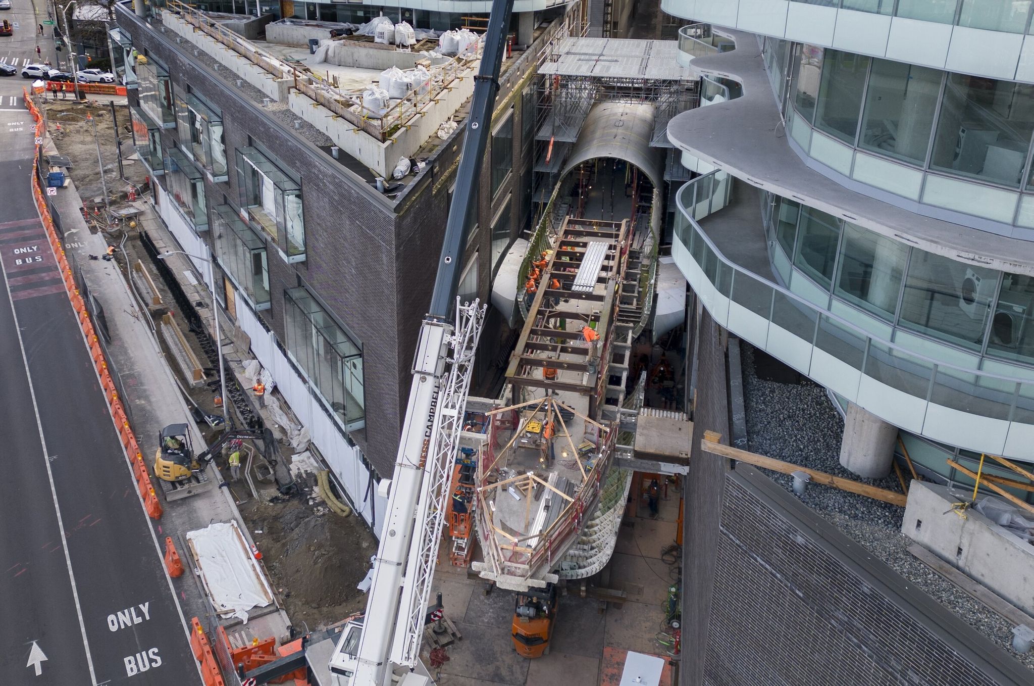 While workers set a Boeing fuselage between two towers, construction equipment is blocking a general-purpose lane on Denny Way used by drivers to reach Yale Avenue and southbound I-5. City staff called this blockage a kind of 'test run' for when the red bus lane shifts to the right this summer, which will permanently close access from Denny/Yale to I-5. (Ellen M. Banner / The Seattle Times)