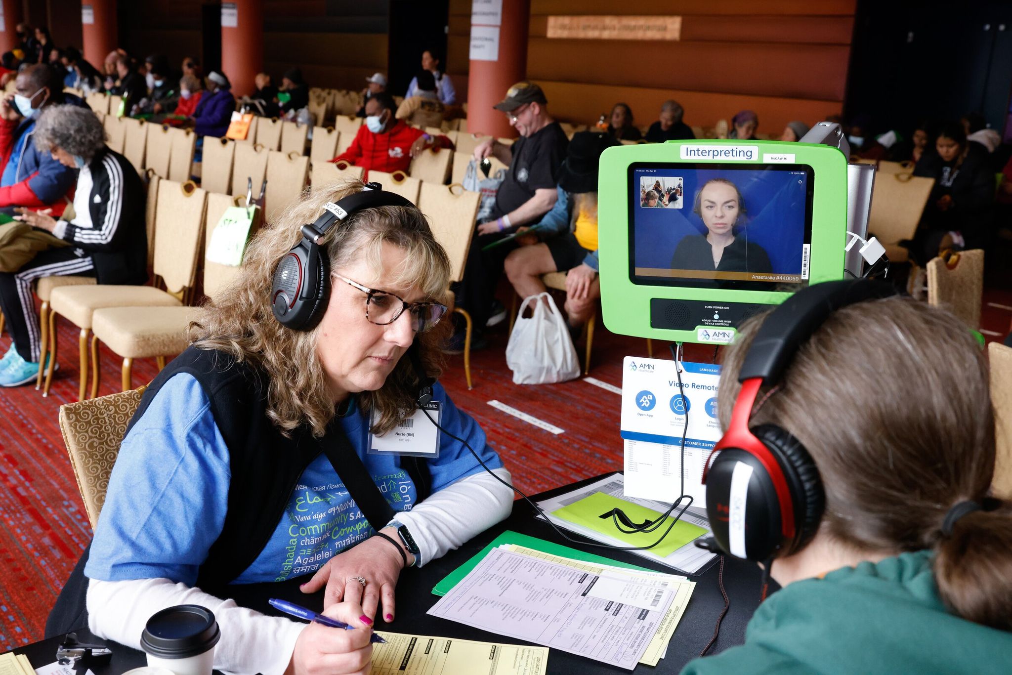 Volunteer Kate Waterman, who normally works as an ER nurse at Whidbey Health (left), assists Vita Kovalchuk (right) and an on‑screen translator speaking Ukrainian at the Seattle/King County clinic. (Karen Ducey / The Seattle Times)
