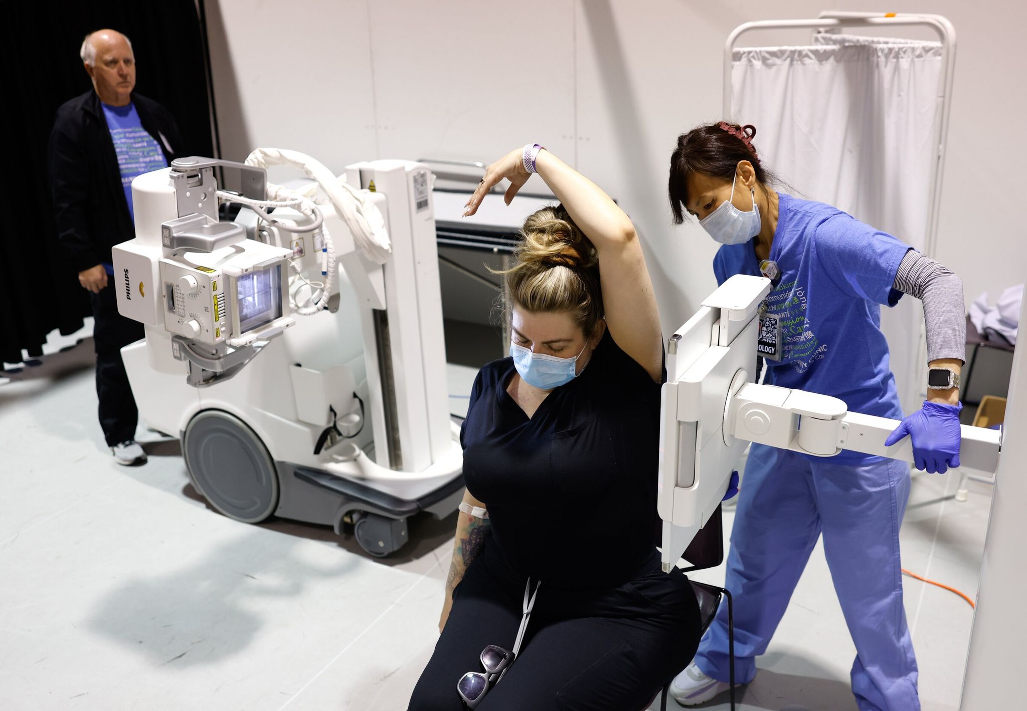 Ray Barnes, X‑ray tech on the right, with Rod Seavers, X‑ray tech behind, positions Tamar Kirk (center) for a spinal X‑ray at the Seattle/King County clinic on Thursday. (Karen Ducey / The Seattle Times)
