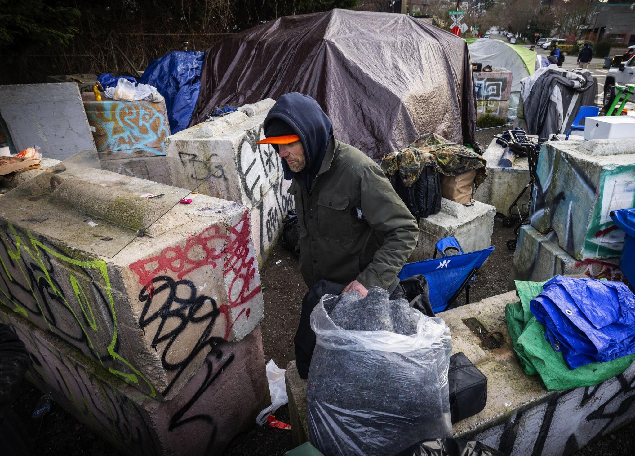 A man who did not give his name but agreed to be photographed packs up his things before the city of Seattle clears an encampment next to the Burke-Gilman Trail in Northwest Seattle on Feb. 12. (Ken Lambert / The Seattle Times)