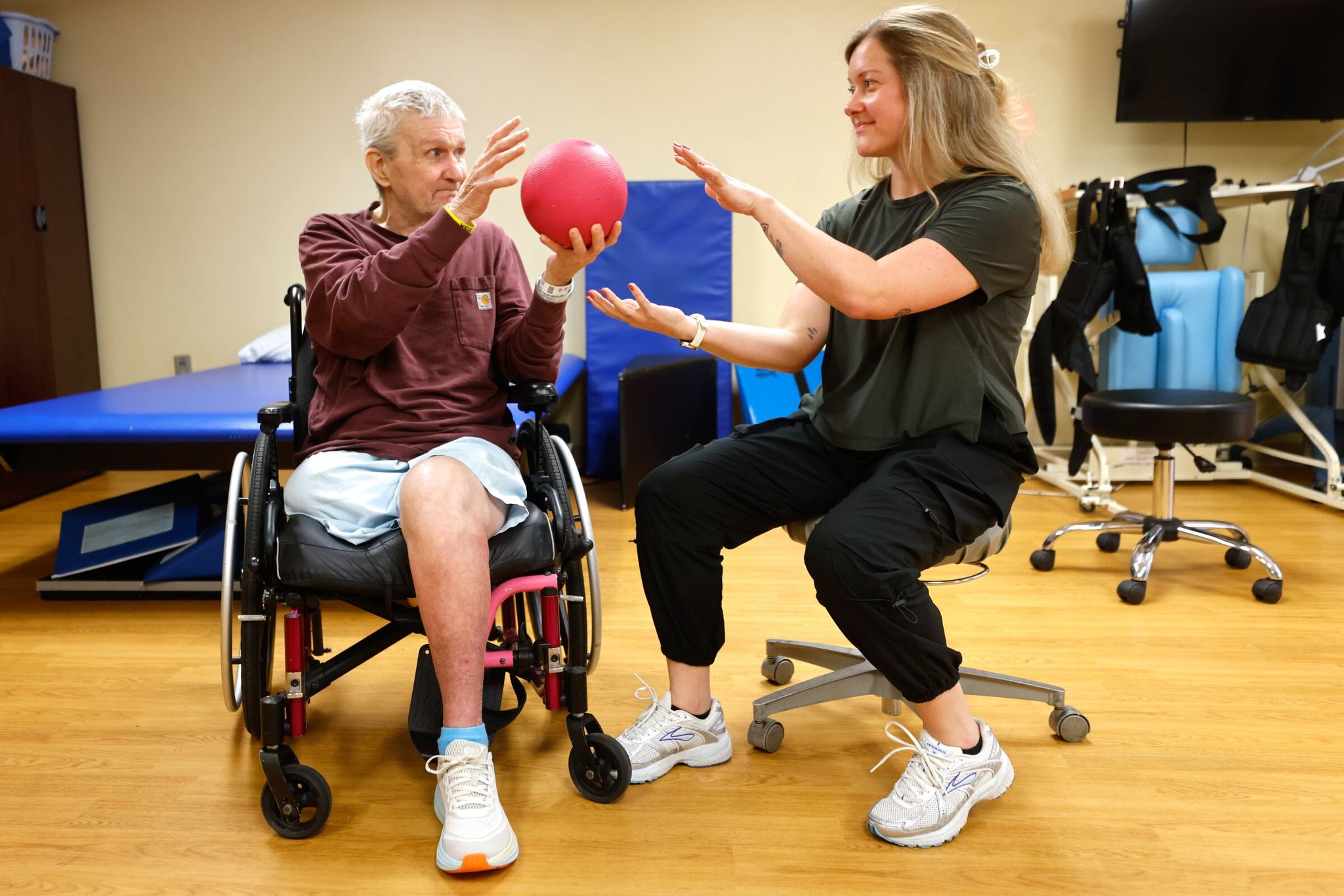 Allen Horne, 78, left, exercises with a weighted ball with Jen Newman, rehabilitation director and physical therapist at Queen Anne Healthcare, a skilled nursing and rehabilitation facility in Seattle. (Karen Ducey / The Seattle Times)