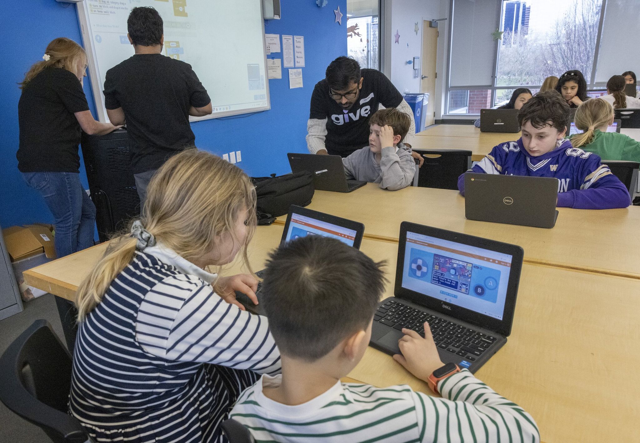 Sunil Nanjappa Ganesh Murthy, top center, a software developer at Microsoft, helps Samson Tsimbalyuk during an AI class at the Bellevue Boys & Girls Club in December. The class is part of the Microsoft Elevate Washington initiative, which has now issued $75,000 grants to 10 Washington school districts to explore ways that AI may help solve school challenges. The move comes amid debates about the impact of AI use in broader society and in schools. (Ellen M. Banner / The Seattle Times, 2025)