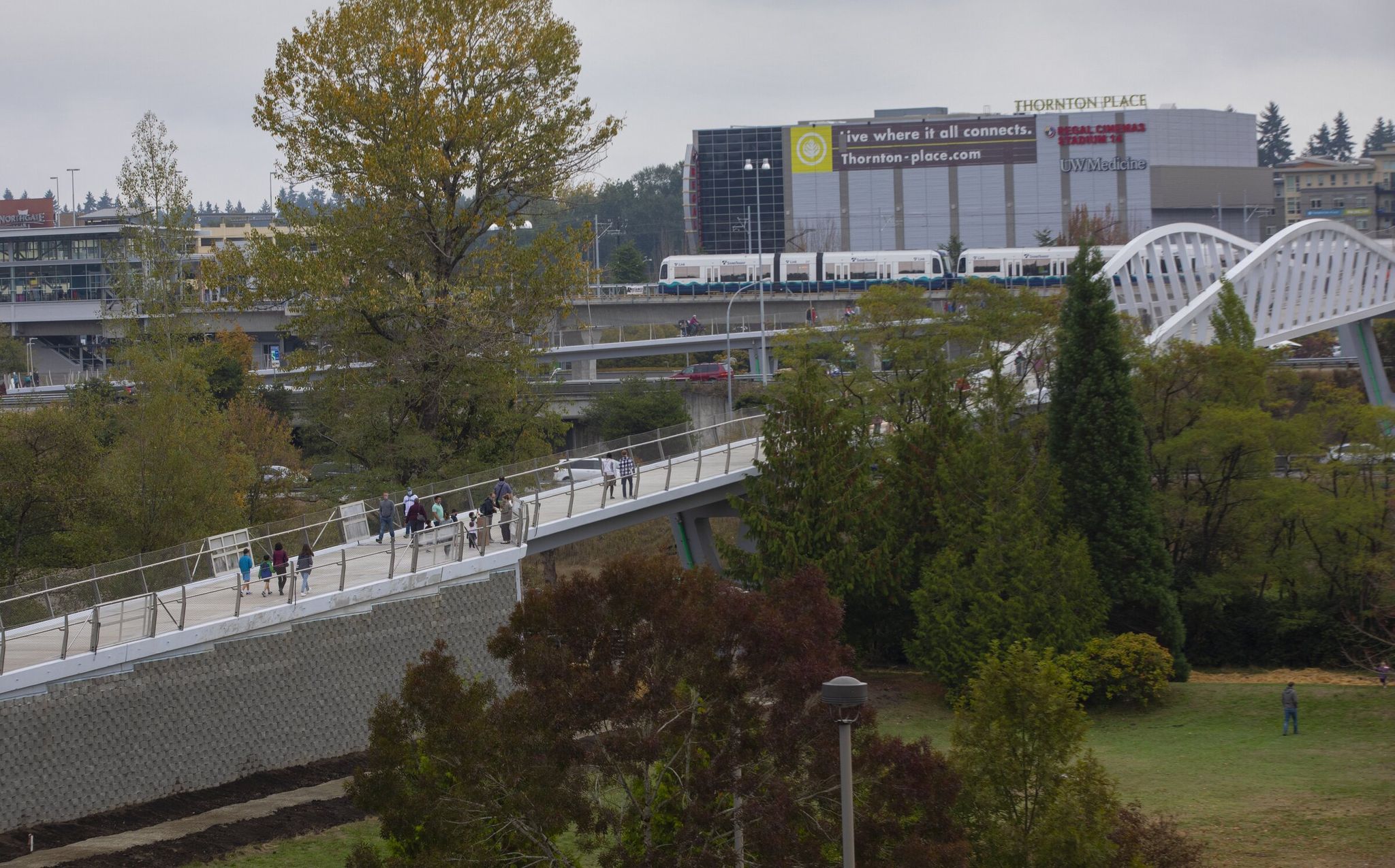 As a train heads toward the Northgate light rail station, people walk across the John Lewis Memorial Bridge at North Seattle College, which has joined the YMCA to explore opening a new, publicly accessible pool at the college. (Ellen M. Banner / The Seattle TImes)
