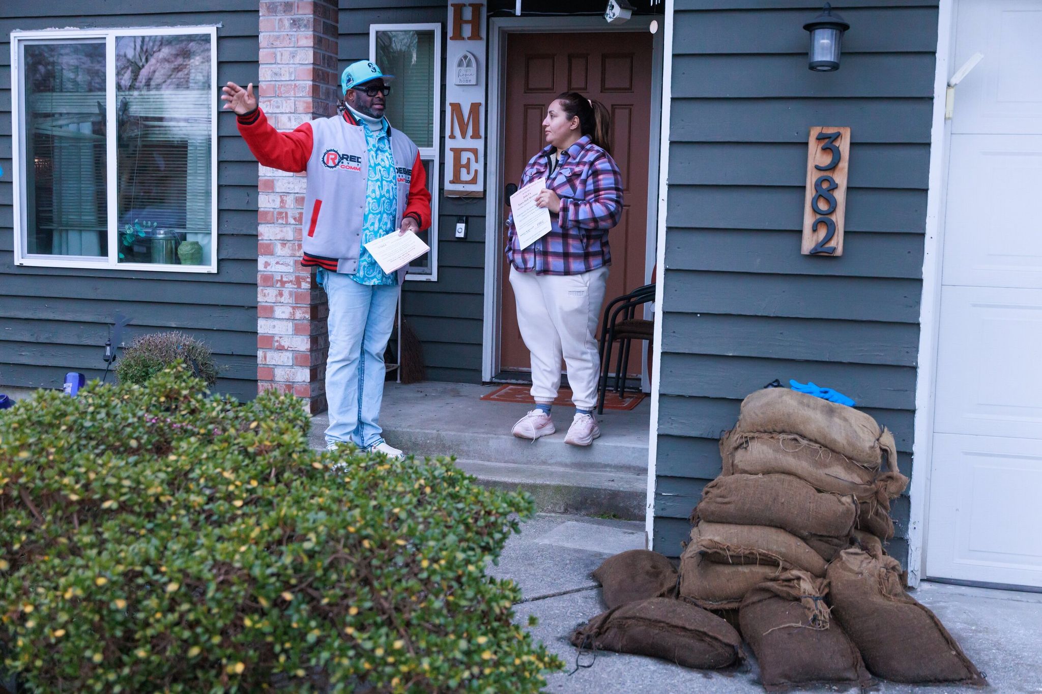 Pastor Lawrence K. Bowles III talks with Lilli Castro on her porch. Bowles organized a meeting for flood victims and brought attorneys who this spring filed a lawsuit against King County and the county flood control district. Castro estimates her family suffered about $65,000 in damage to their home and car. (Erika Schultz / The Seattle Times)