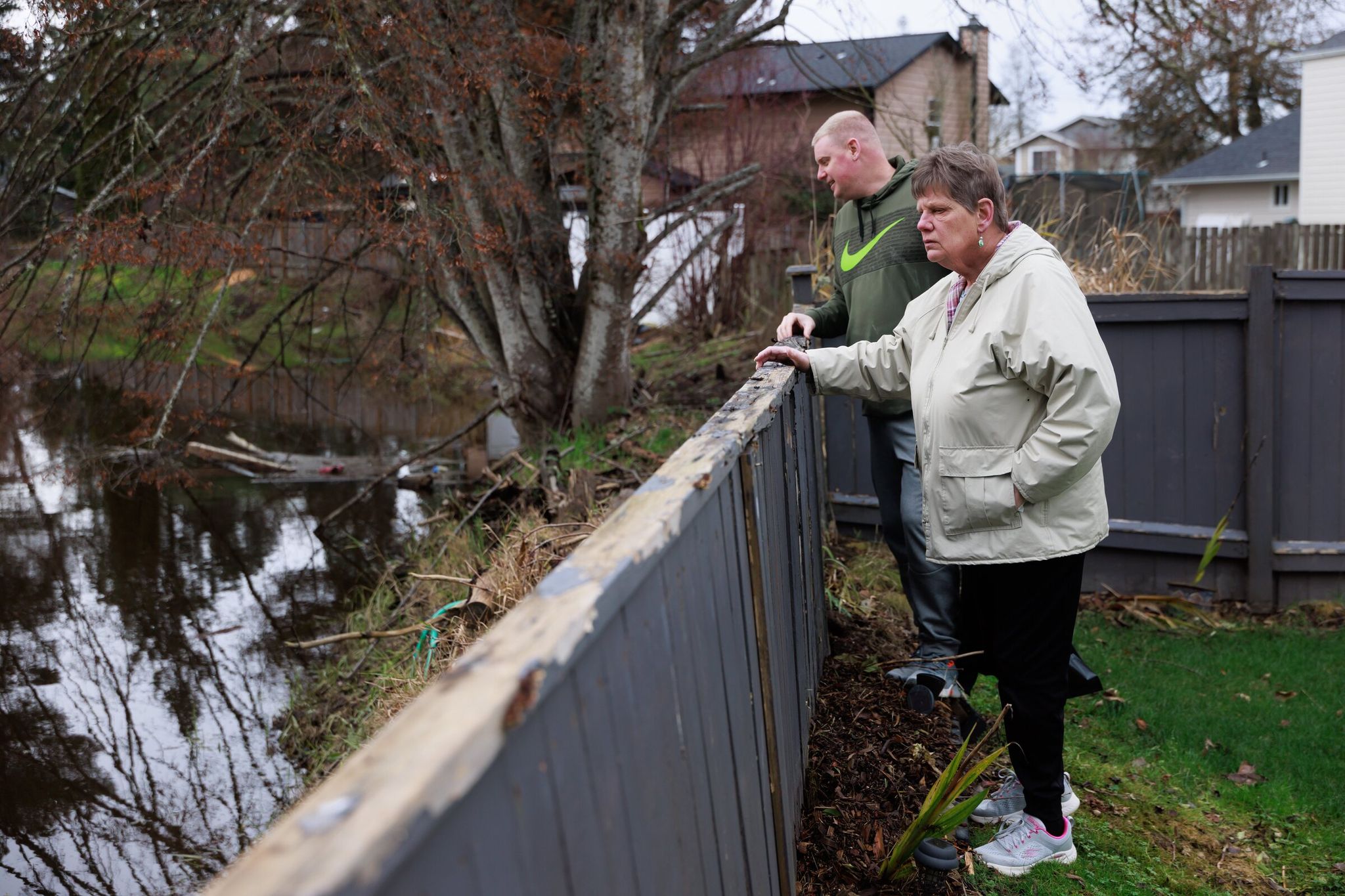 Trevor Curtis and his mother Joanne Curtis look at the Government Canal that borders their backyard. After the flood, crews worked on the canal, which connects to the White River. (Erika Schultz / The Seattle Times)