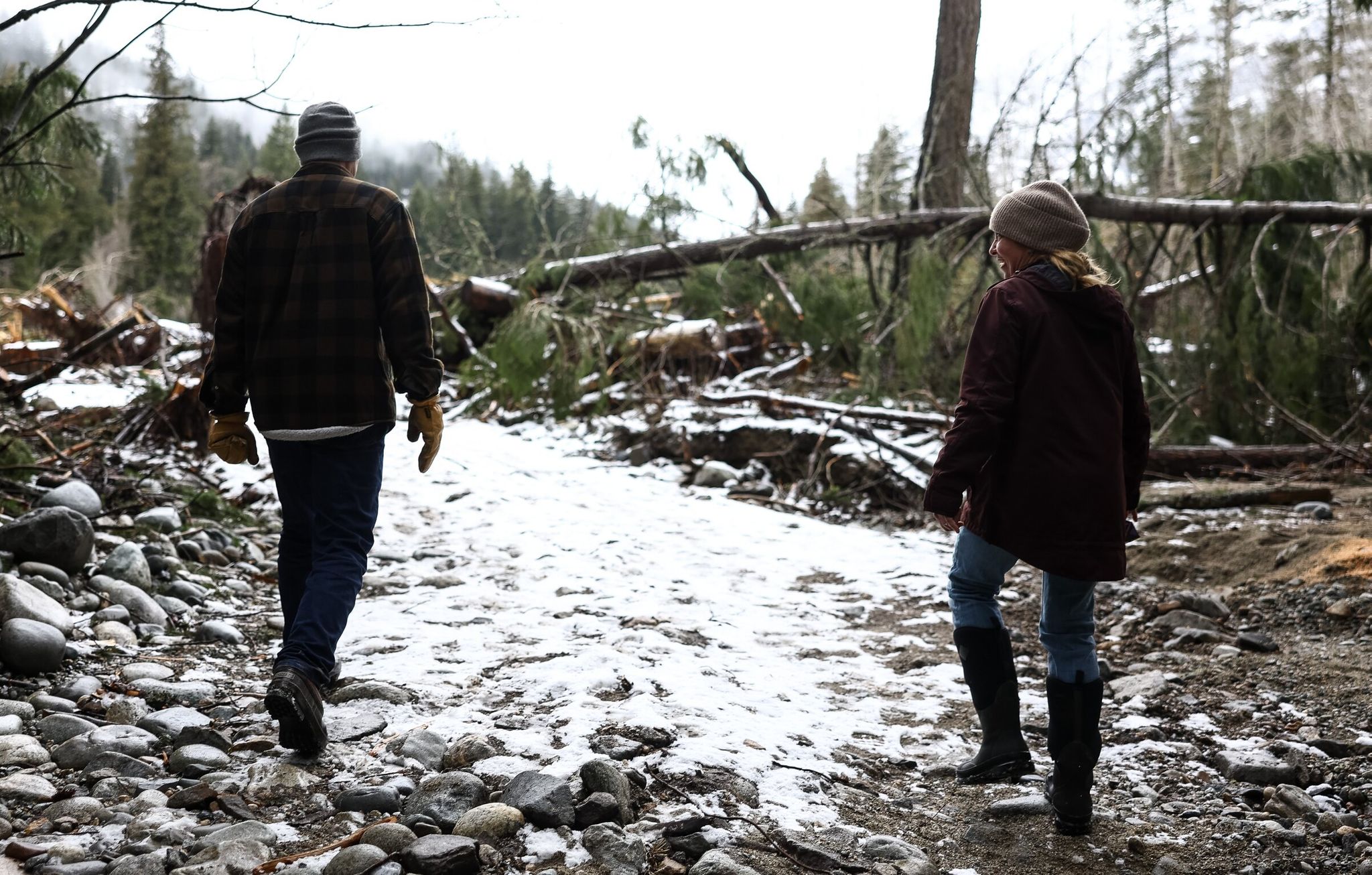 Neighbors Jake Courtney (left) and Mandy Kitchell walk along the washed-out Company Creek Road in February in Stehekin. (Nick Wagner / The Seattle Times)