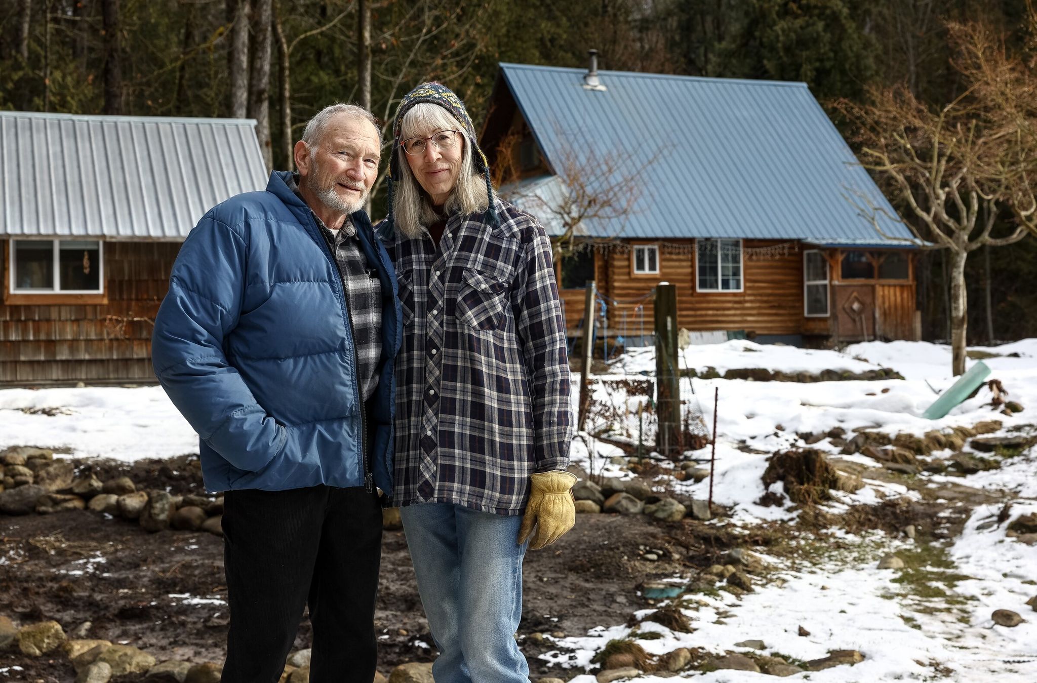 David and Janetta Kurth outside their home in February in Stehekin. David was home when the Stehekin River flooded the valley in December, fully surrounding the Kurths’ property. (Nick Wagner / The Seattle Times)