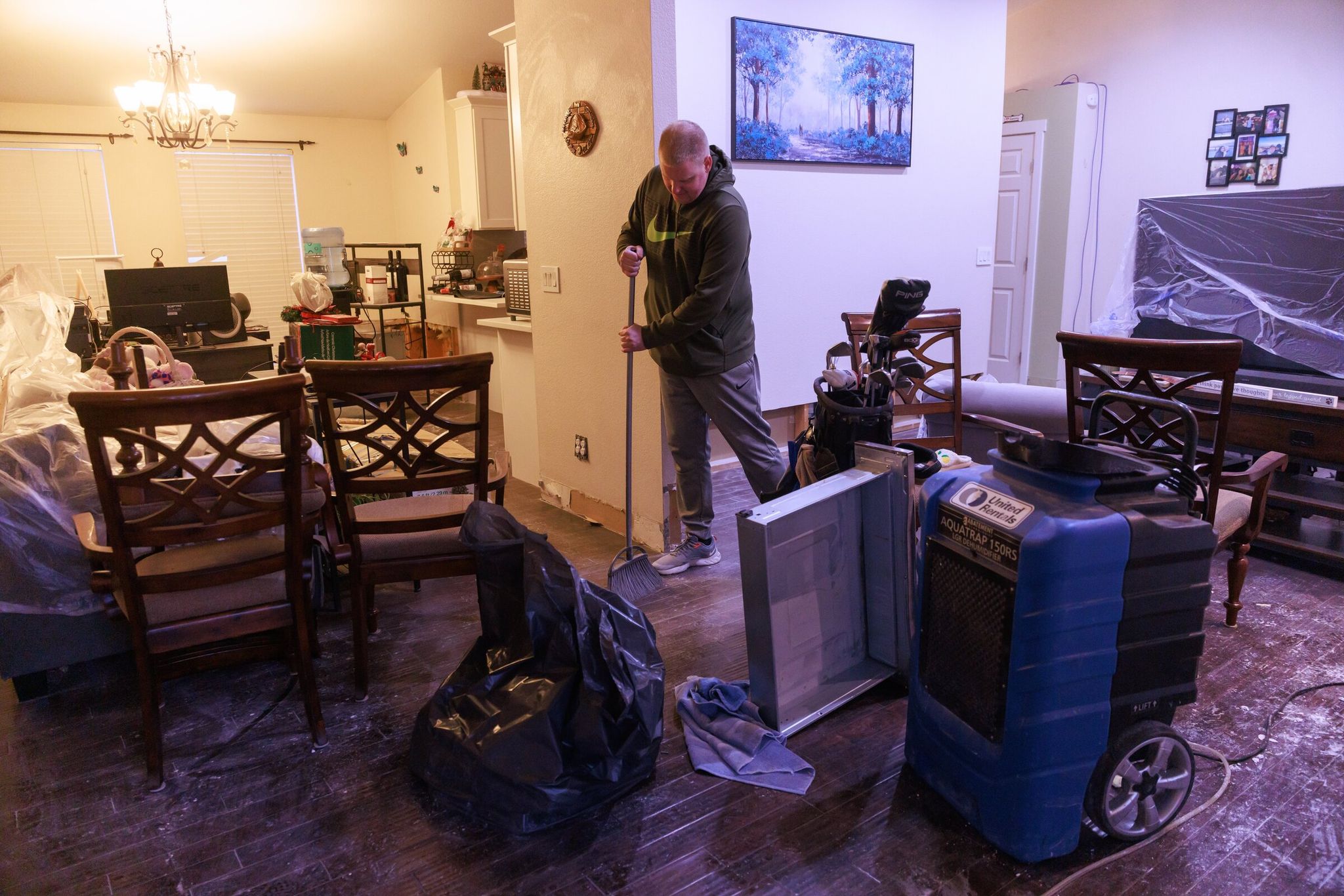 Trevor Curtis cleans mud and debris from the floor of his home in Pacific. After the flood, he and his partner, Emmy Guerra, were expecting the birth of their firstborn child. (Erika Schultz / The Seattle Times)