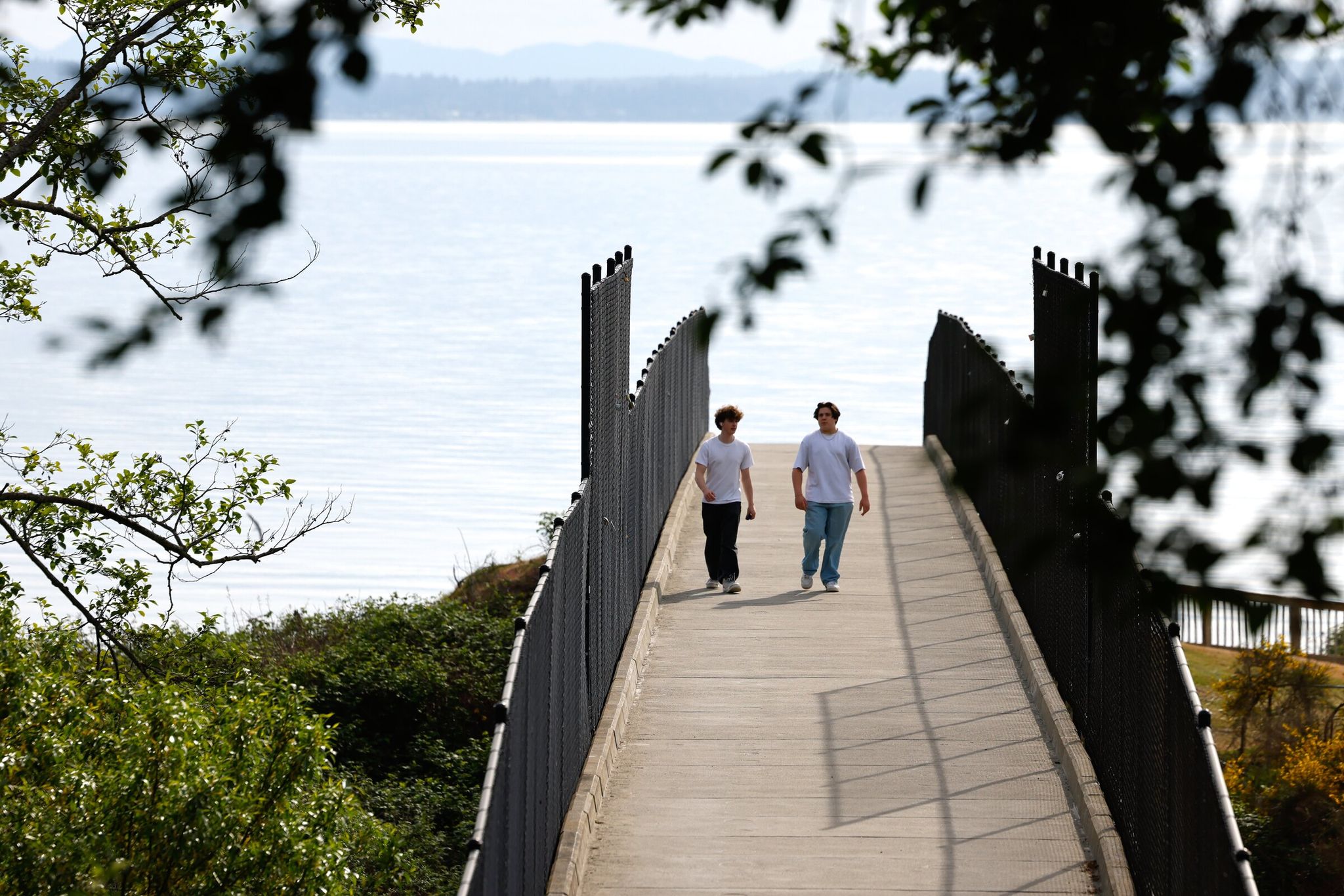 Wyatt Doan, 17, left, and Nick Fonken, 17, walk over the railroad bridge at Richmond Beach Saltwater Park toward the beach in Shoreline this month. (Karen Ducey / The Seattle Times)