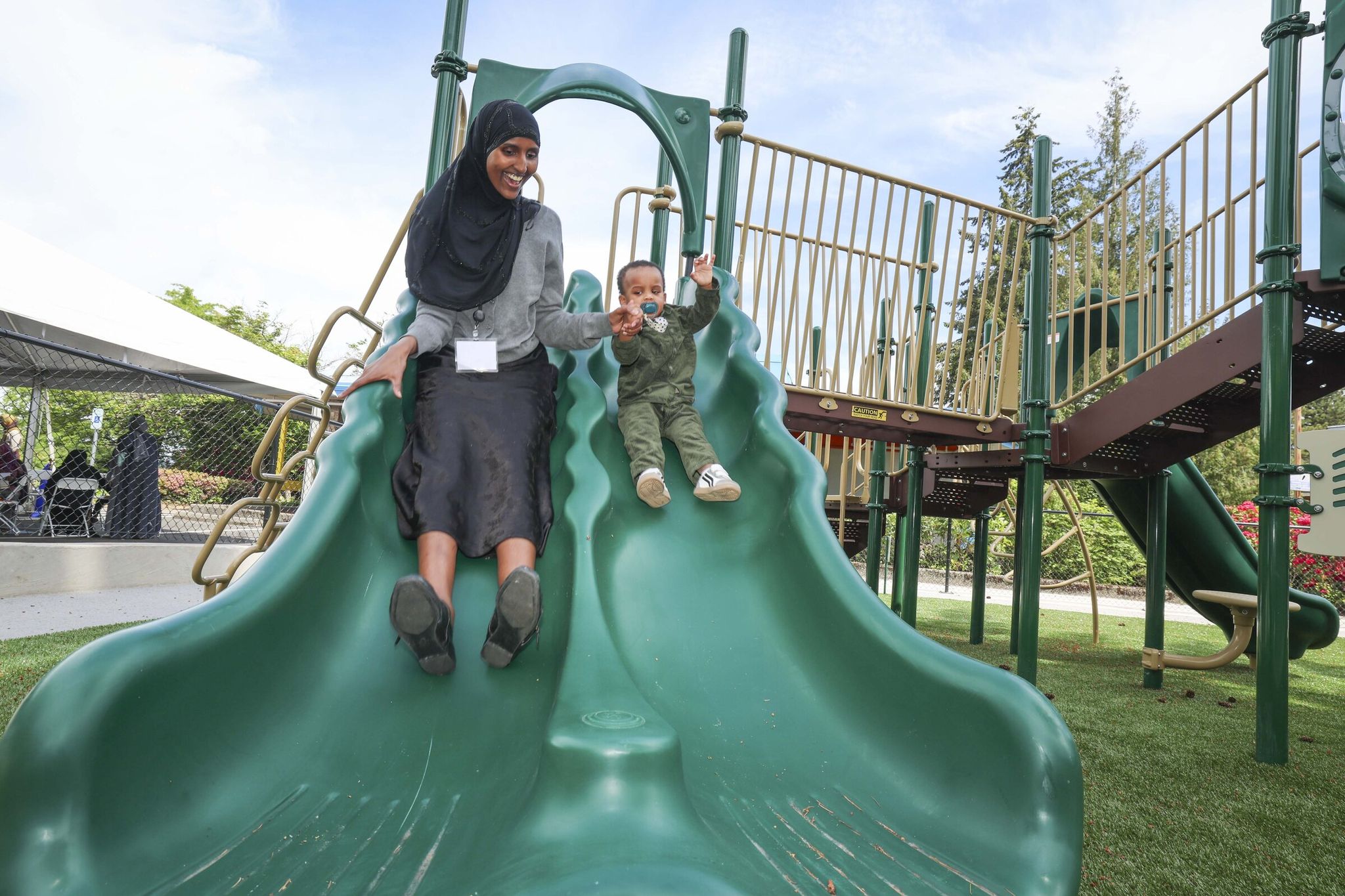 Dunio Jarato, 27, left, and one of her twin sons Iyad Abdi, 1, right, share a moment in the playground during the grand opening of The Voices of Tomorrow Center for Learning and Healing in Tukwila on Thursday, May 21. (Ivy Ceballo / The Seattle Times)