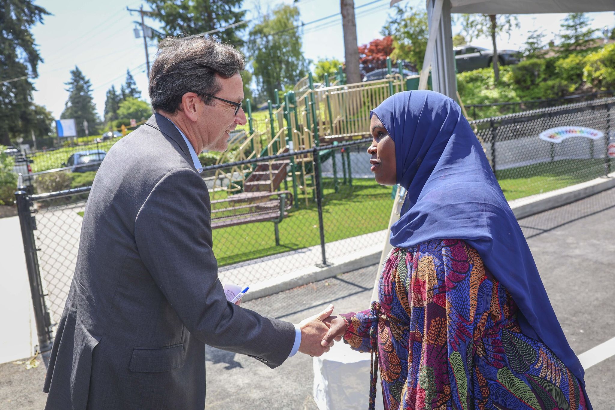 Governor Bob Ferguson, left, greets Voices of Tomorrow CEO Zamzam Mohamed during the grand opening of the Voices of Tomorrow Center for Learning and Healing in Tukwila on Thursday, May 21. (Ivy Ceballo / The Seattle Times)