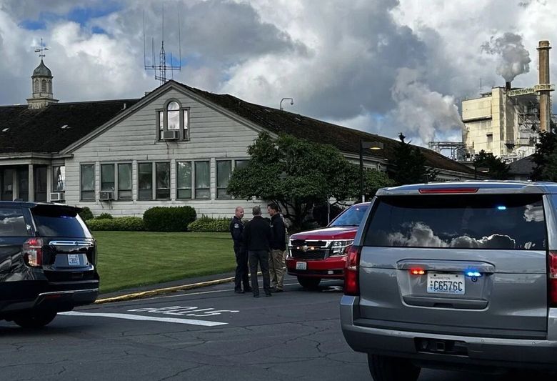 Officials, including Longview Police Chief Robert Huhta talk outside the Nippon Dynawave Packaging Co. on Tuesday, May 26, in Longview, after a reported implosion at the pulp and paper mill. (Matthew Esnayra / The Daily News)