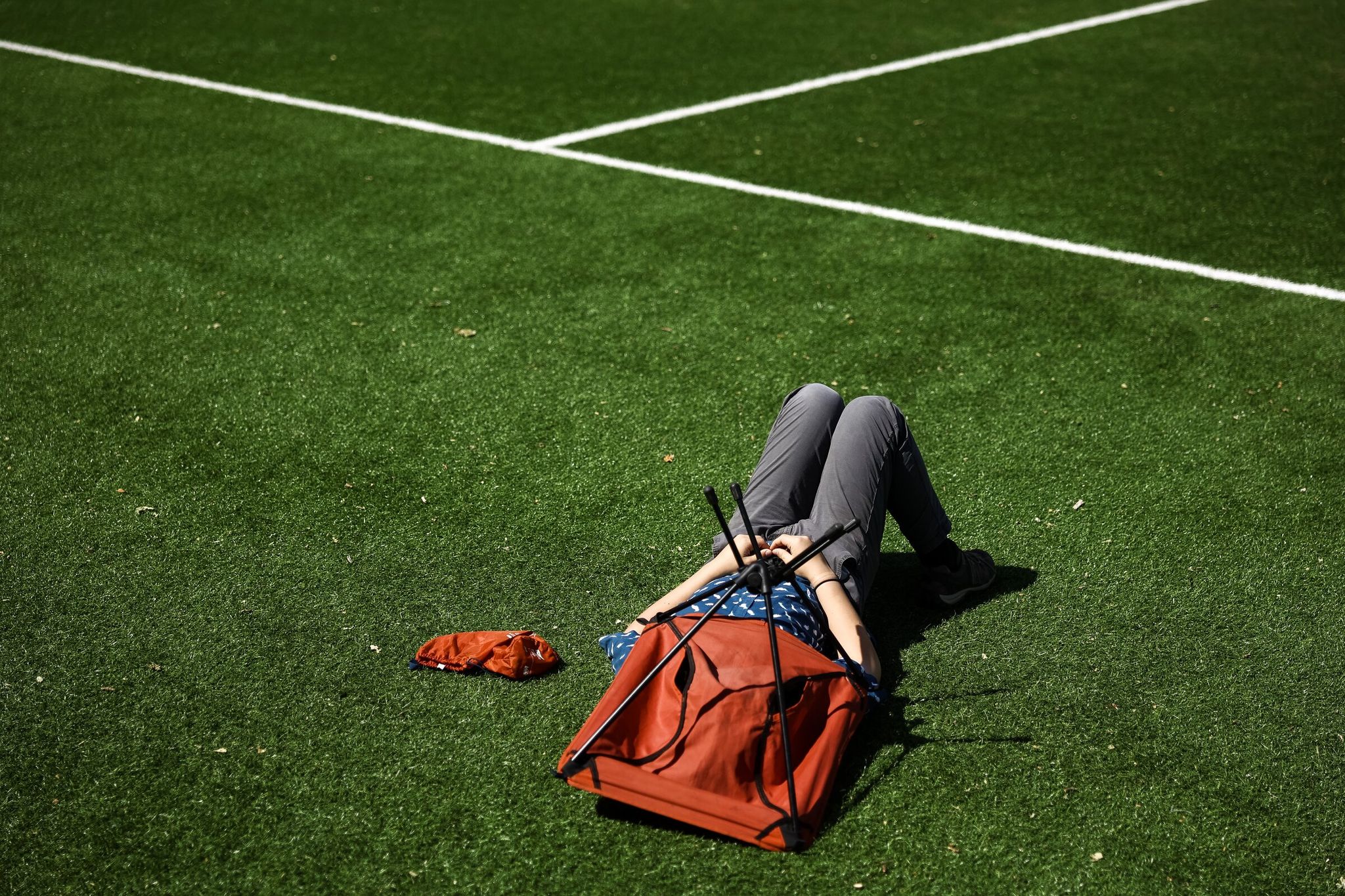 A spectator covers their head while resting during a recreational adult soccer match at Georgetown Playfield. (Nick Wagner / The Seattle Times)