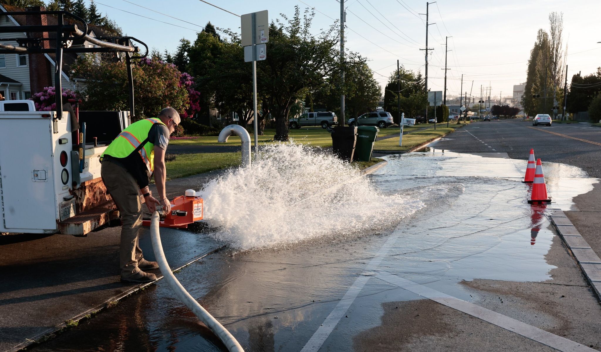 City crews open fire hydrants and send the water down the drains in the street in Longview, Cowlitz County, on Wednesday, May 27, 2026. On Tuesday a tank containing hazardous liquid at Nippon Dynawave Packaging Co., seen down the street in this photo, imploded, causing death and injuries. (Karen Ducey / The Seattle Times)