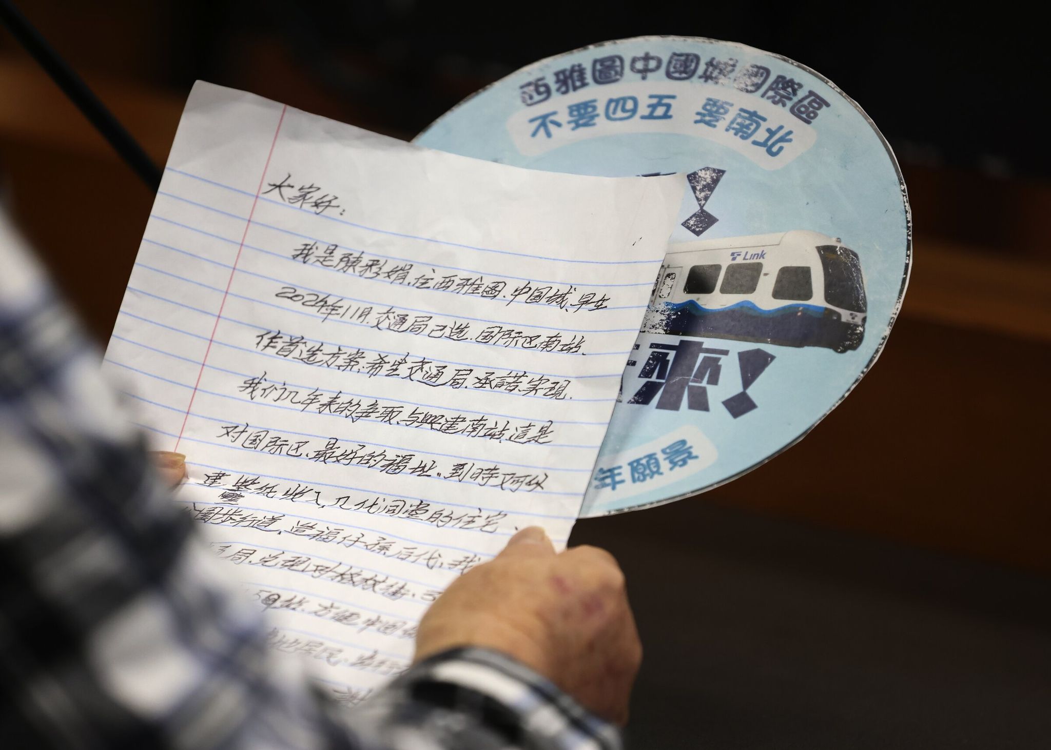 A woman reads her statement in Cantonese before the Sound Transit board vote on Thursday. The translated statement urged the board to keep promises and support restoring the Graham Street station. (Ken Lambert / The Seattle Times)