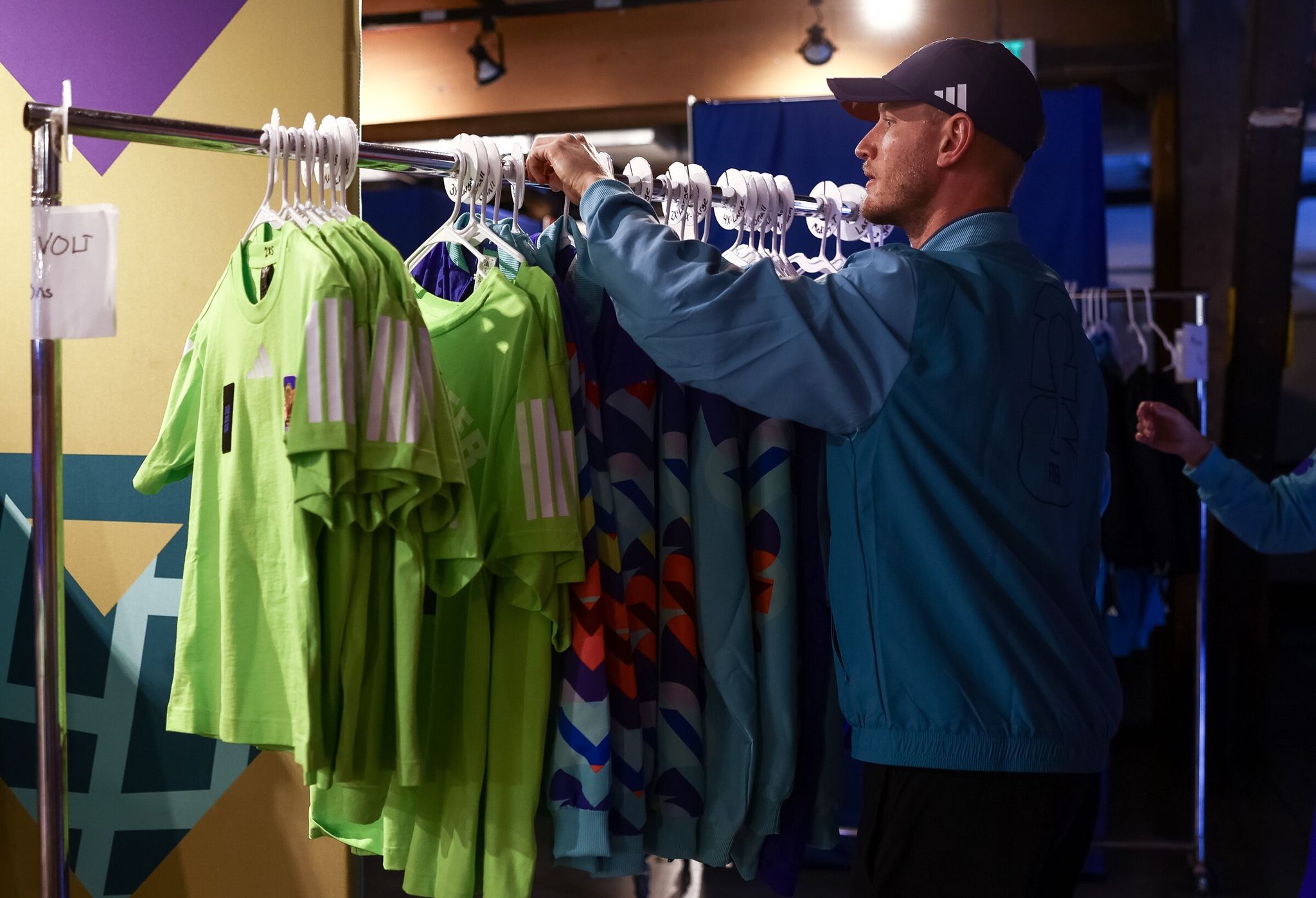 Kade Norton, FIFA uniform coordinator, pulls a rack of volunteer T-shirts and jackets for fitting on May 20 in Seattle. (Nick Wagner / The Seattle Times)