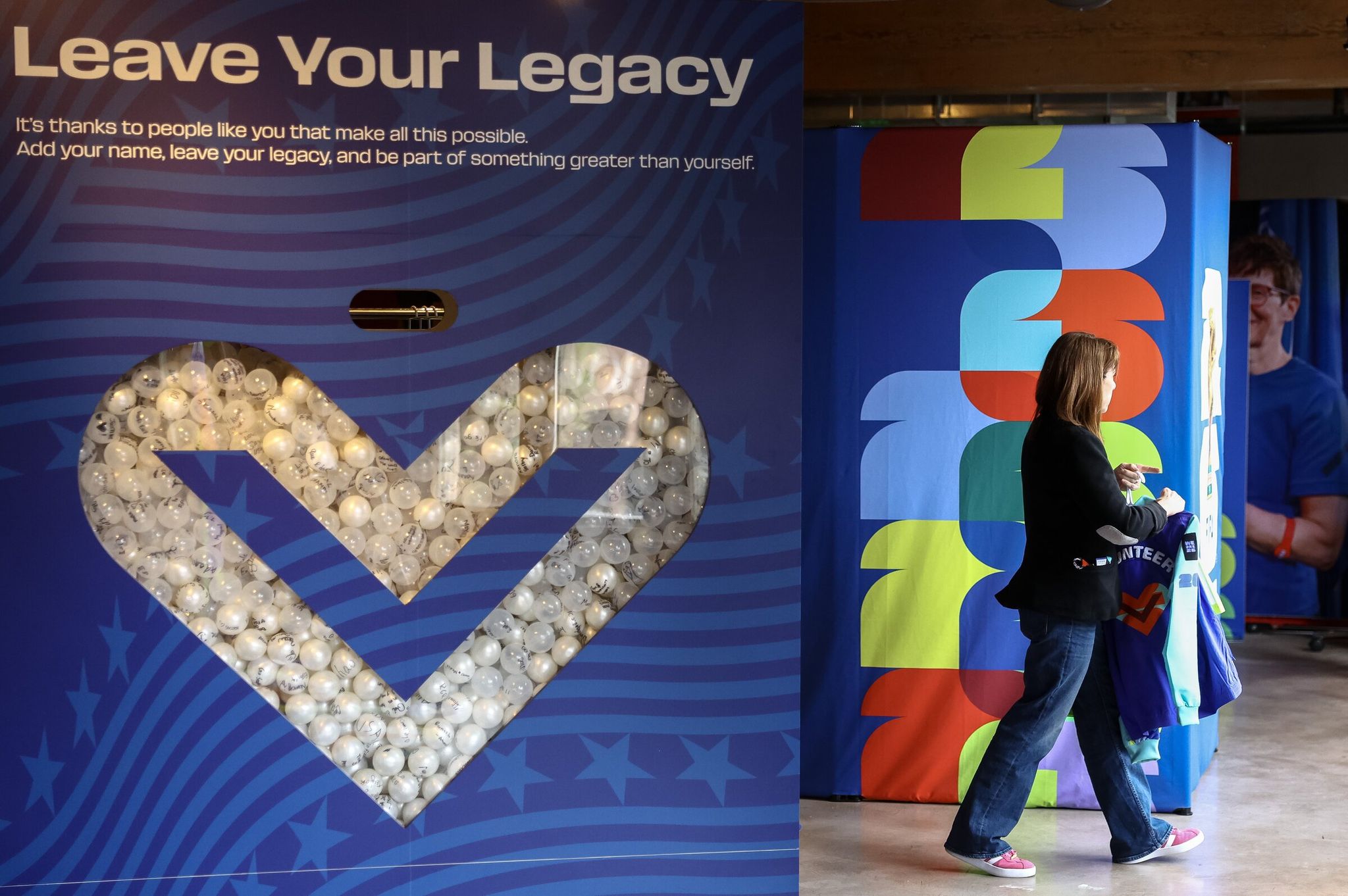 A FIFA World Cup volunteer carries uniform items into a fitting room for try-on on May 20 in Seattle. (Nick Wagner / The Seattle Times)