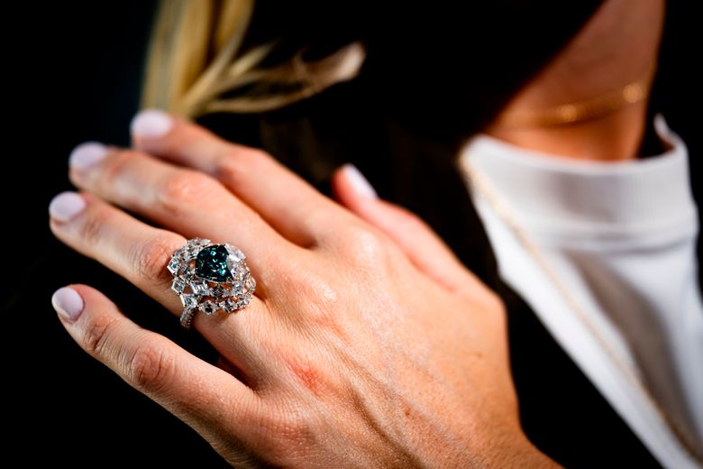 A Christie’s employee displays “The Ocean Dream”, the largest fancy vivid blue-green diamond, weighting 5.50 carats, estimated at 7,000,000 to 10,000,000 CHF during a preview at Christie’s in Geneva, Switzerland, Thursday, May 7, 2026. (Jean-Christophe Bott/Keystone via AP)