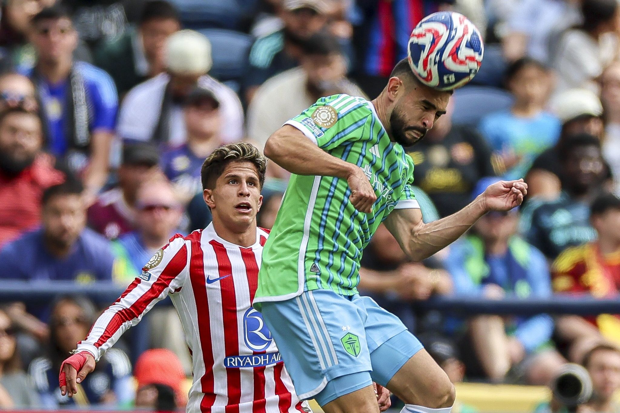Seattle Sounders midfielder Alex Roldan heads the ball while Atletico Madrid forward Julián Simeone watches during the second half of a FIFA Club World Cup group stage match at Lumen Field in June 2025. (Kevin Clark / The Seattle Times)