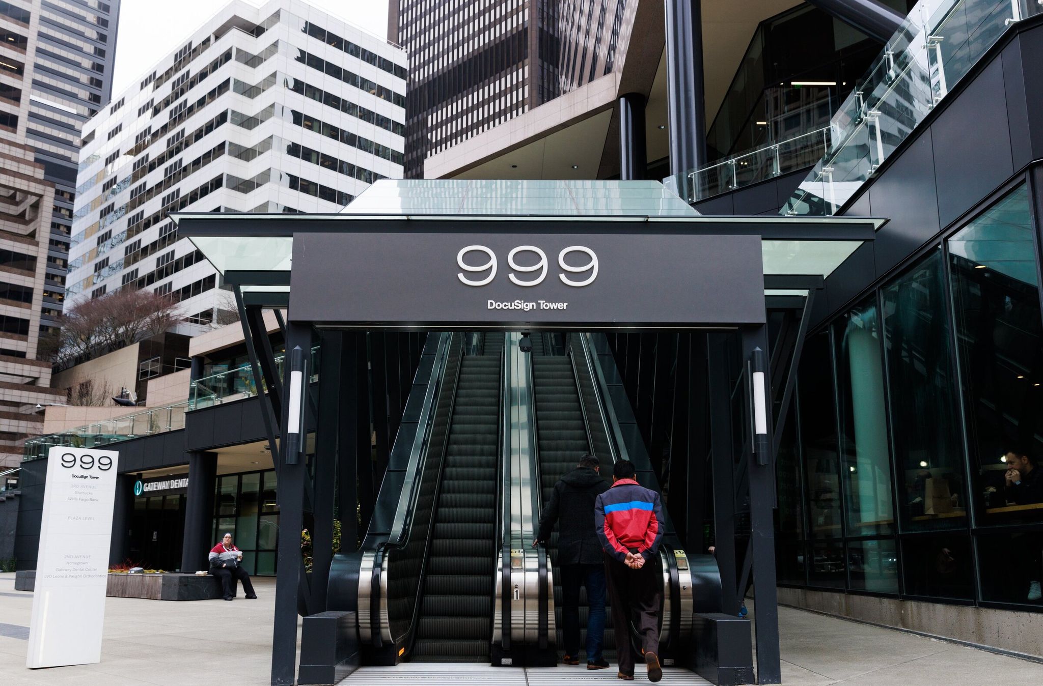 Pedestrians use the escalator leading up to Docusign Tower on Third Avenue in downtown Seattle. (Erika Schultz / The Seattle Times, 2023)