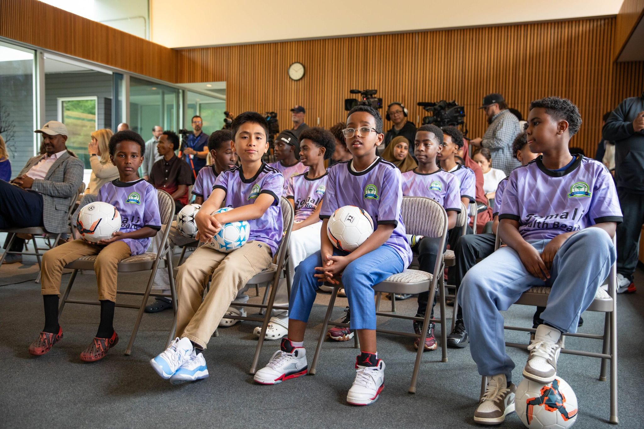 Members of the Somali Health Board Soccer Club youth team from Tukwila show off their purple team jerseys. Seattle Mayor Katy Wilson announced free FIFA World Cup tickets for 1,400 local teens at a Wednesday news conference. (Nicole Pasia / The Seattle Times)