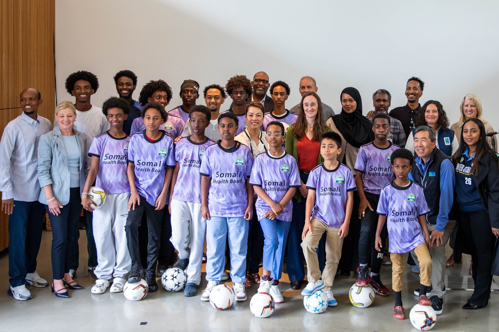 Seattle Mayor Katie Wilson stands with members of the Somali Health Board Soccer Club, members of the Seattle FIFA World Cup 2026 Local Organizing Committee and other community partners during a news conference announcing free World Cup tickets for more than 1,400 local youths and their caregivers. (Nicole Pasia / The Seattle Times)