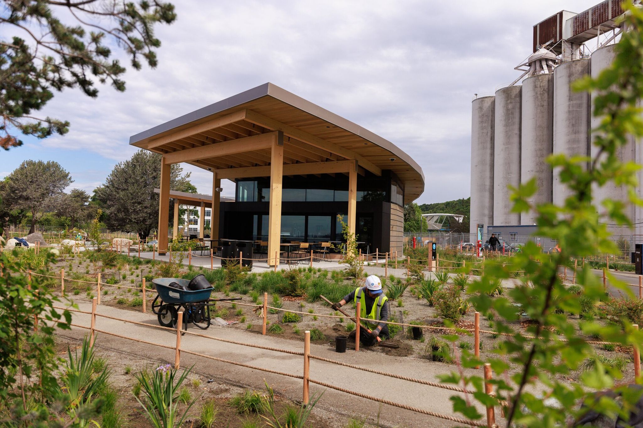 Landscape workers plant vegetation on Wednesday beside a new amenity building called haʔłali, which means “good place” in Lushootseed, in Centennial Park on Elliott Bay in Seattle. The building includes a food kiosk and restrooms. (Erika Schultz / The Seattle Times)