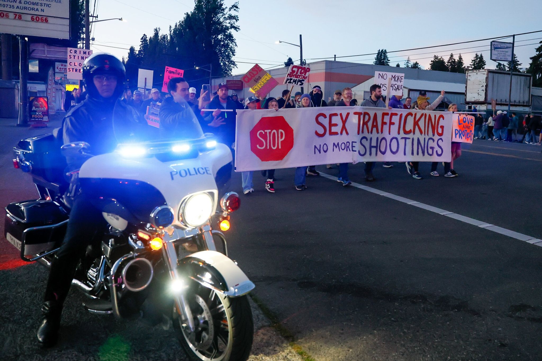 A Seattle Police Department motorcycle officer stops traffic along Highway 99 as neighbors take to the busy road during a march protesting the rise of crime along the busy corridor Saturday in North Seattle. (Jennifer Buchanan / The Seattle Times)
